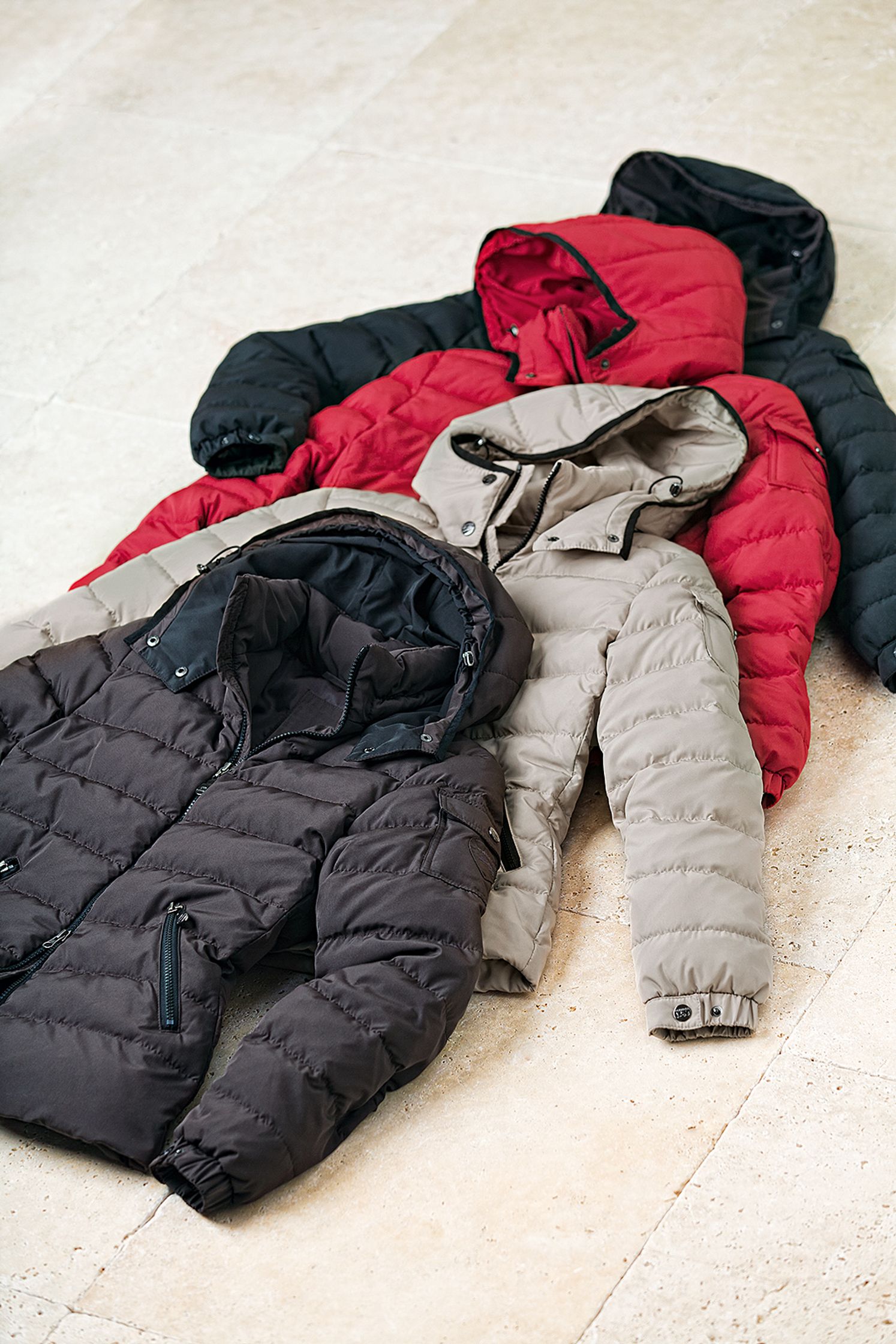 four down jackets laying on a tile floor Bildbearbeitung Hamburg