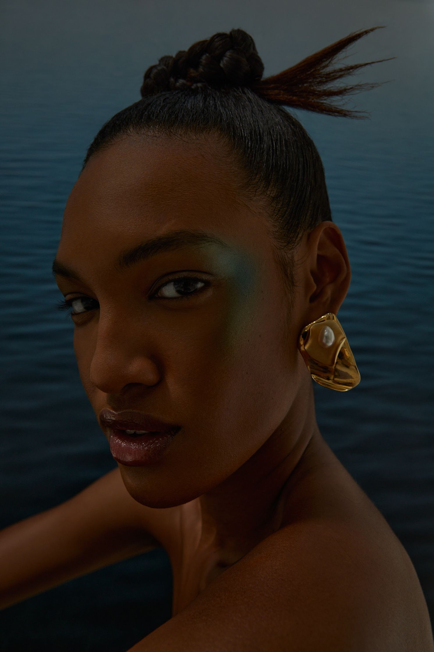 a woman is posing in front of a body of water