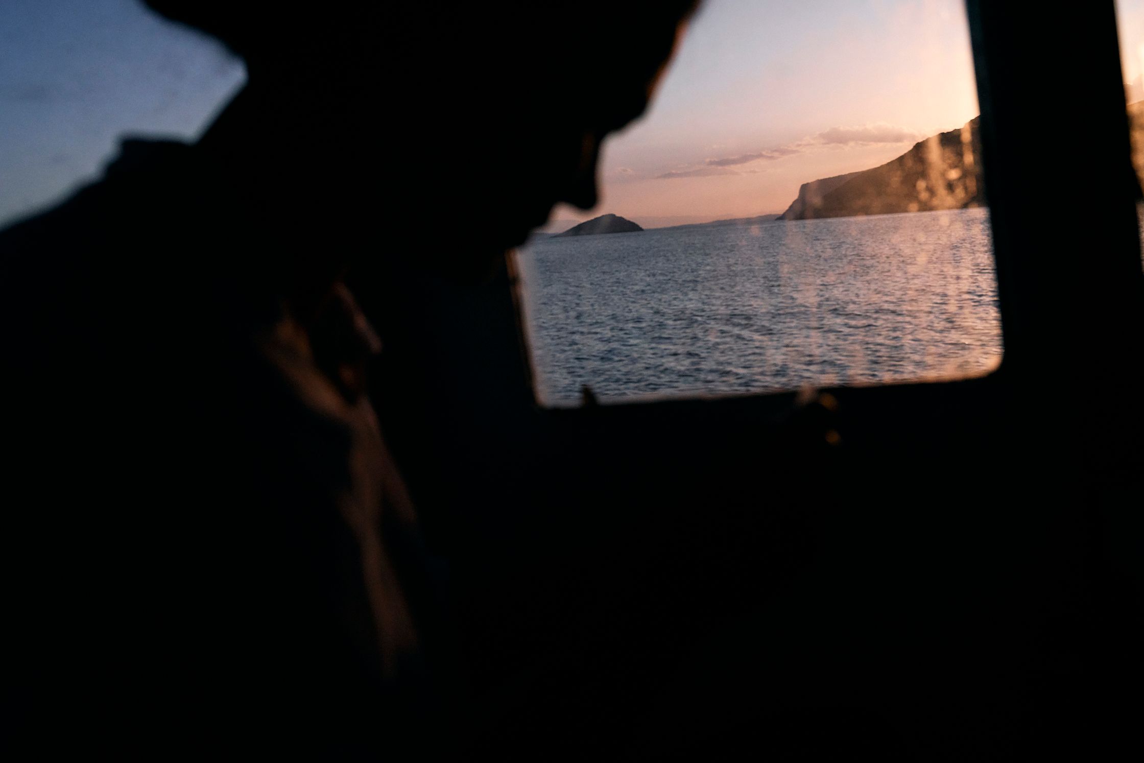 a silhouette of a woman looking out the window of a boat at sunset