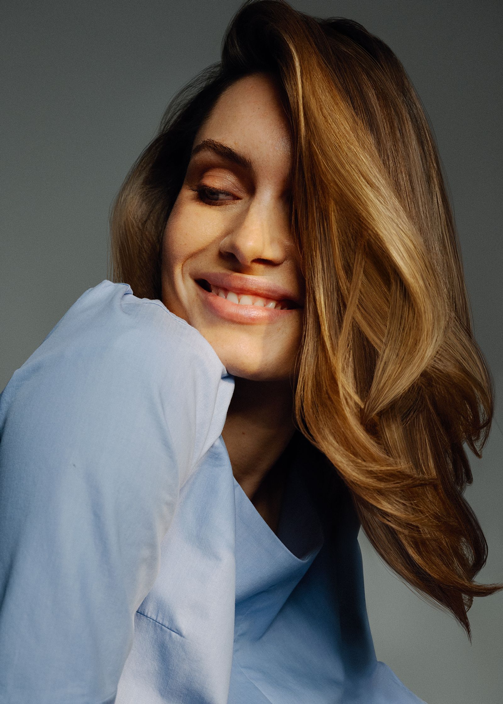 a woman smiling with her eyes closed in a blue shirt