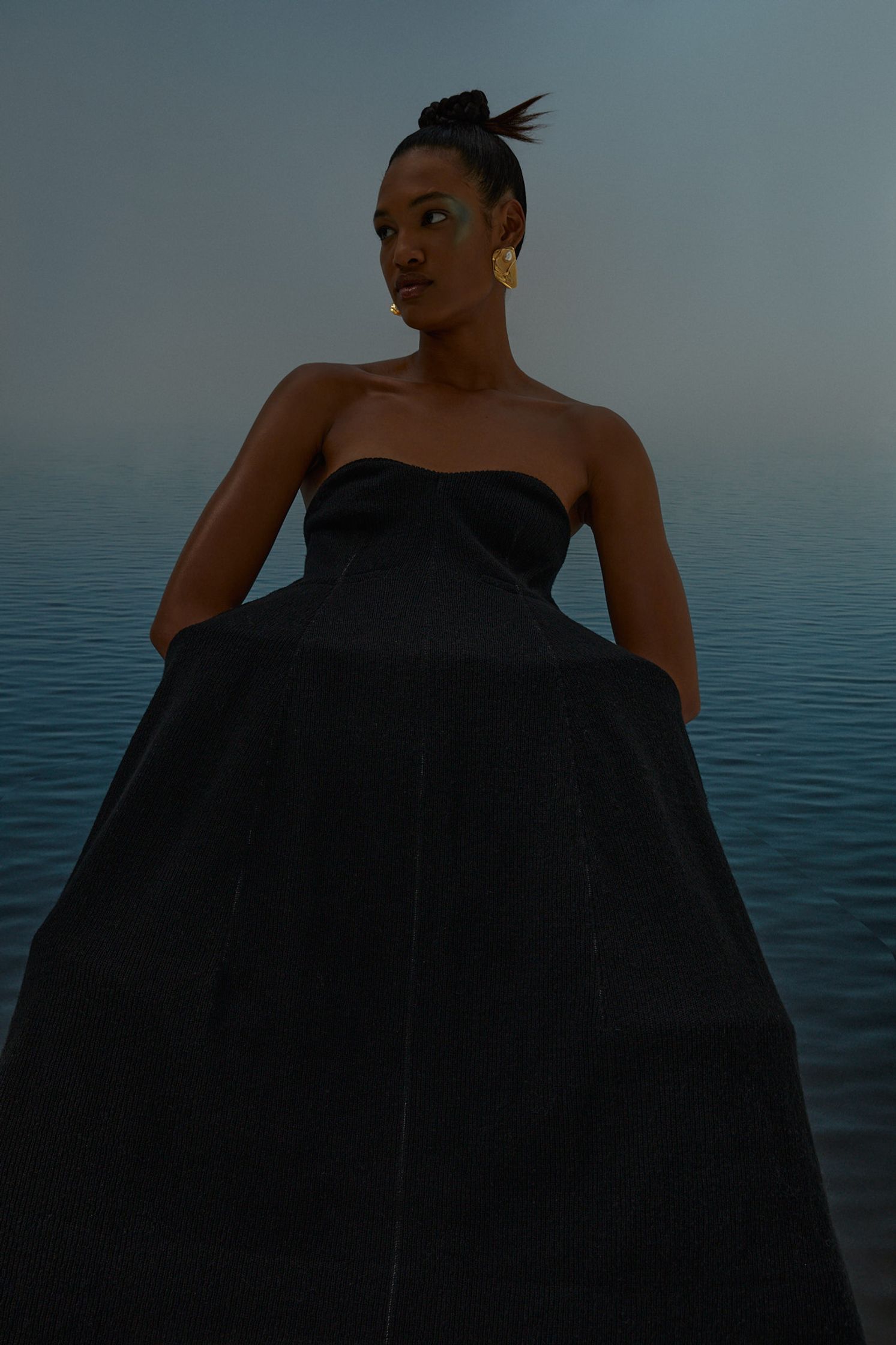 a woman in a black dress sitting in the water