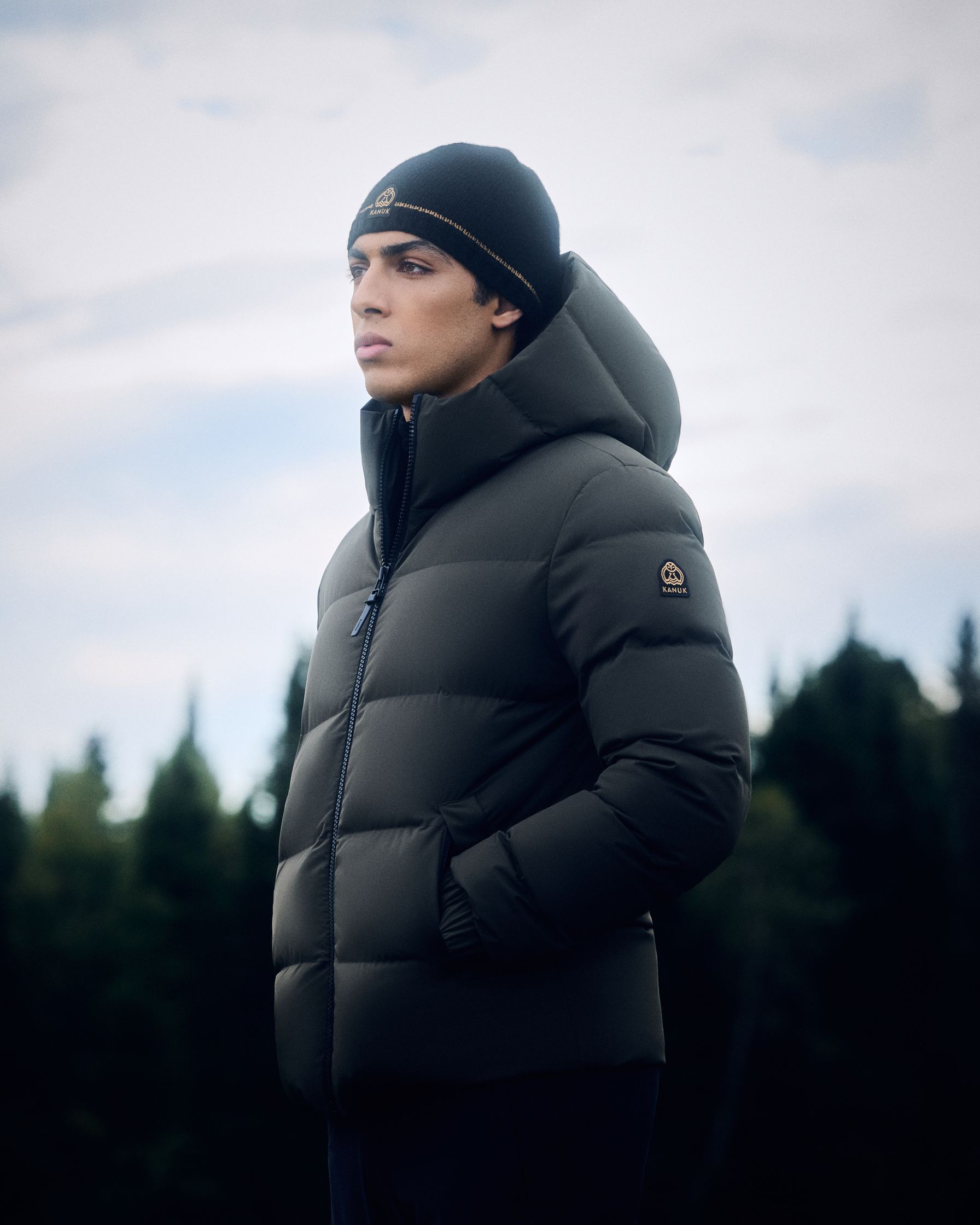 a man in a black puffer jacket standing in a forest