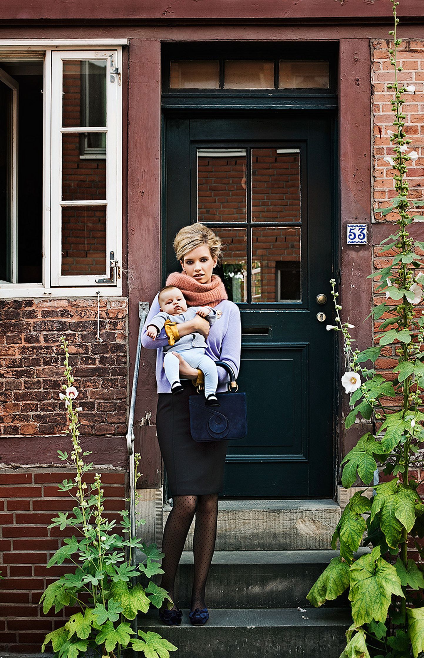 a woman holding a baby on the steps of a building creative retouch and look