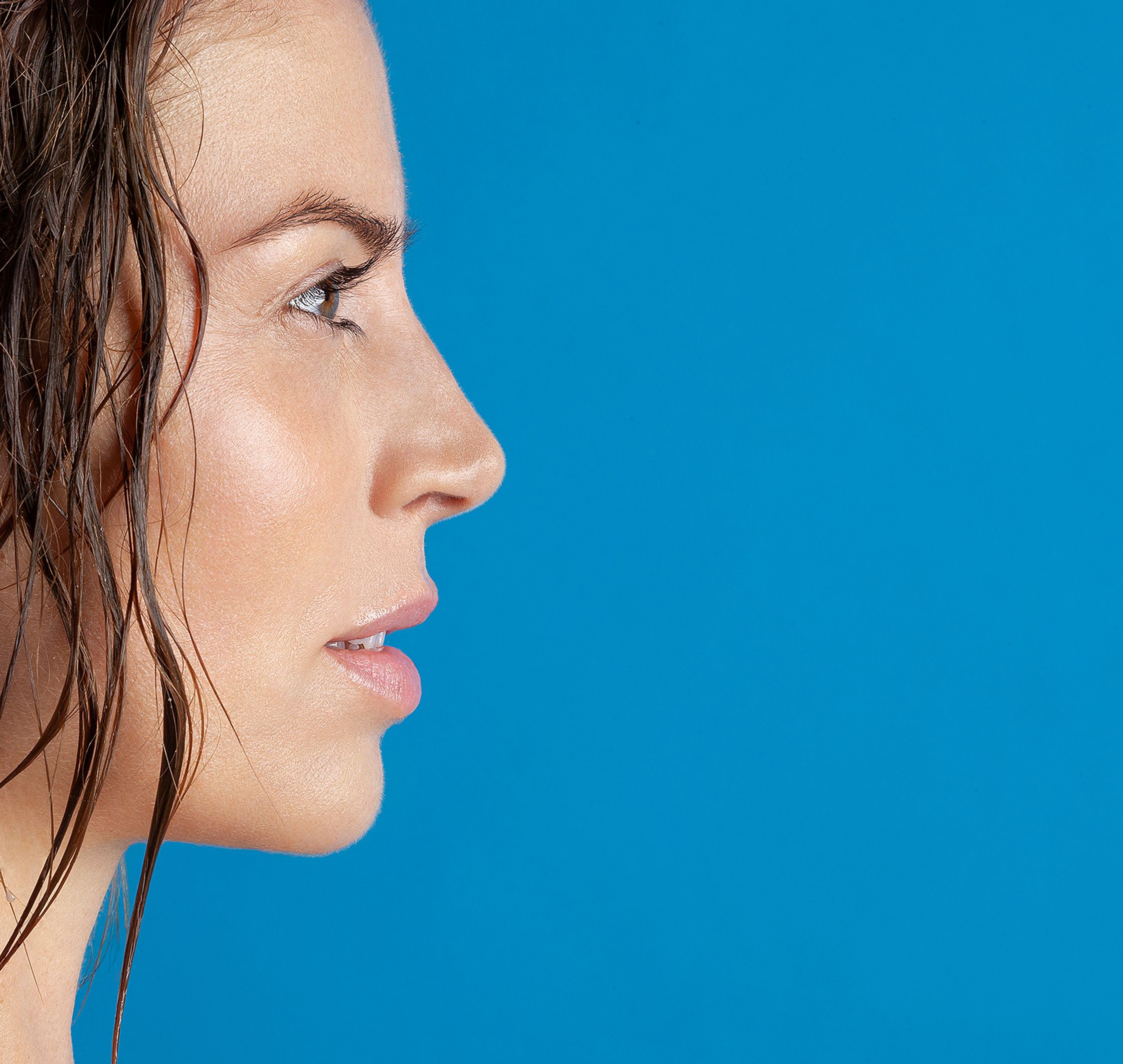 a woman's face with wet hair against a blue background beauty bildbearbeitung