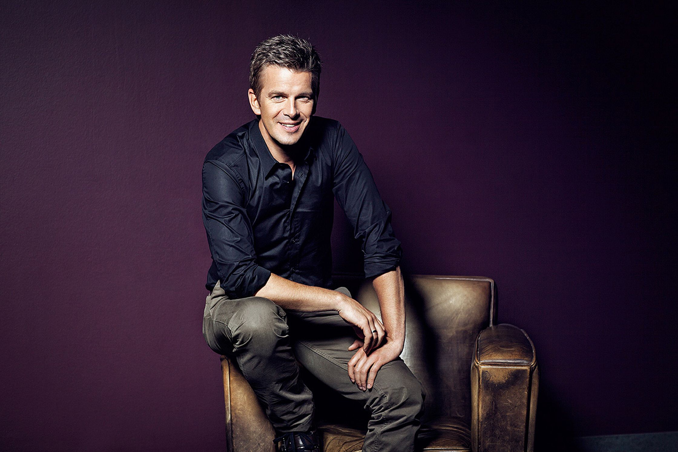 markus lanz sitting on a chair in front of a purple wall
post production by glamtouch