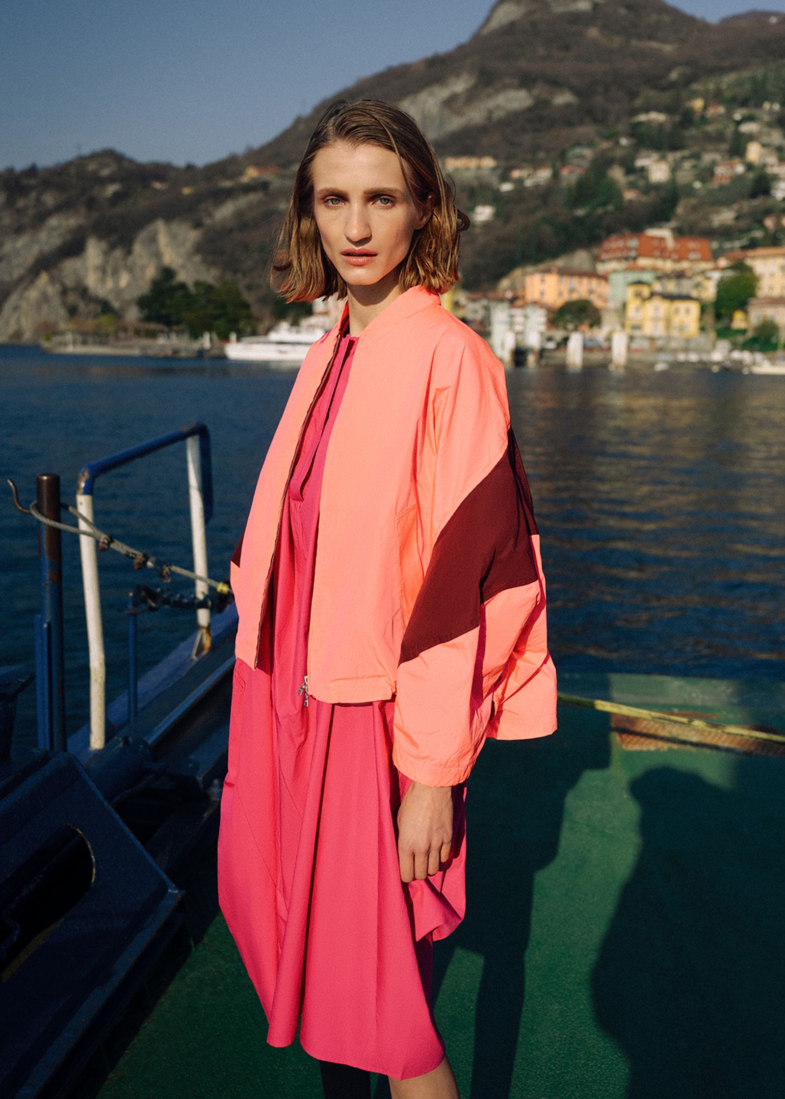 a woman in a pink dress standing on a boat