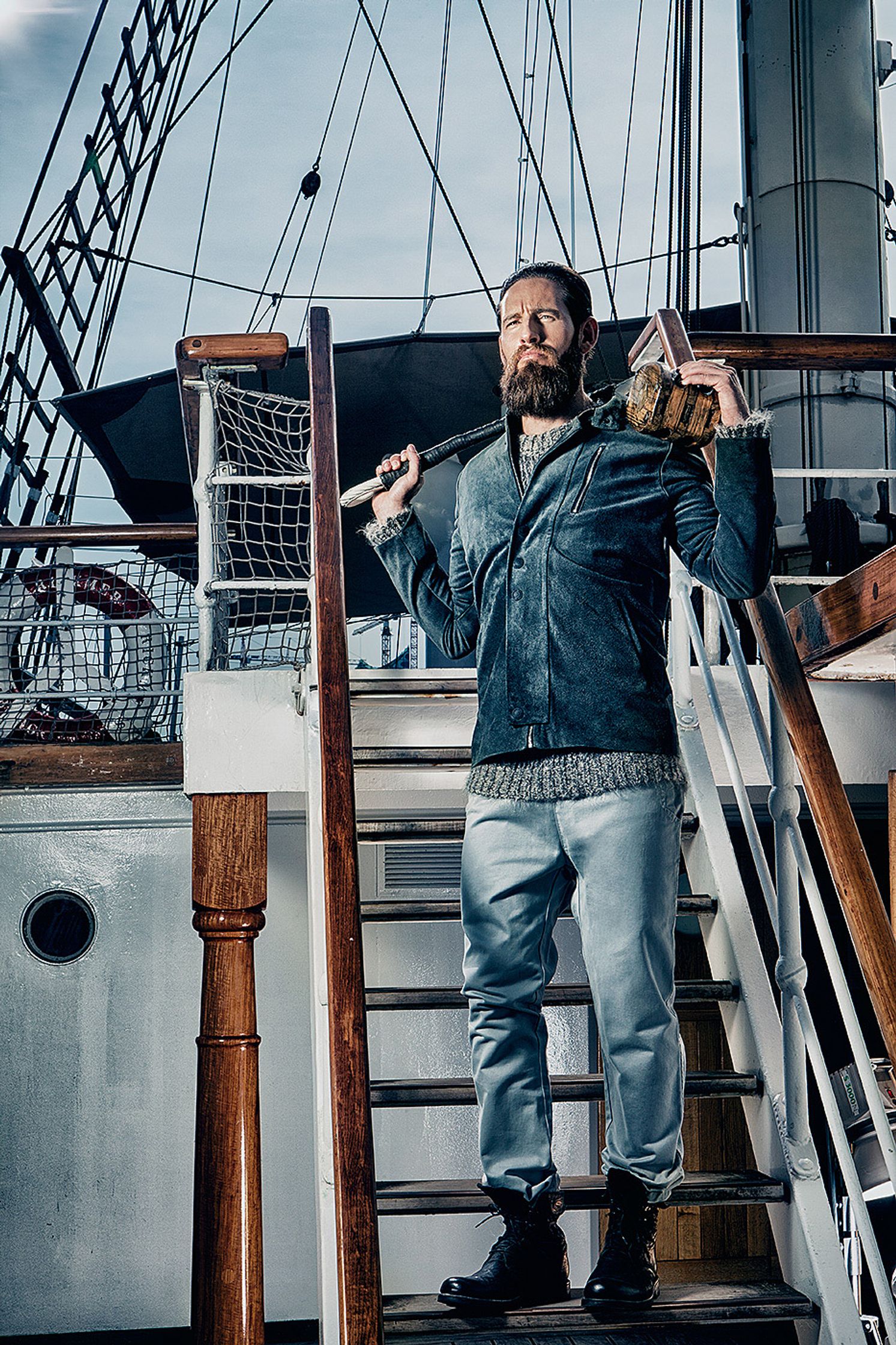 a man with a beard standing on the stairs of a boat Creative Retouching Hamburg