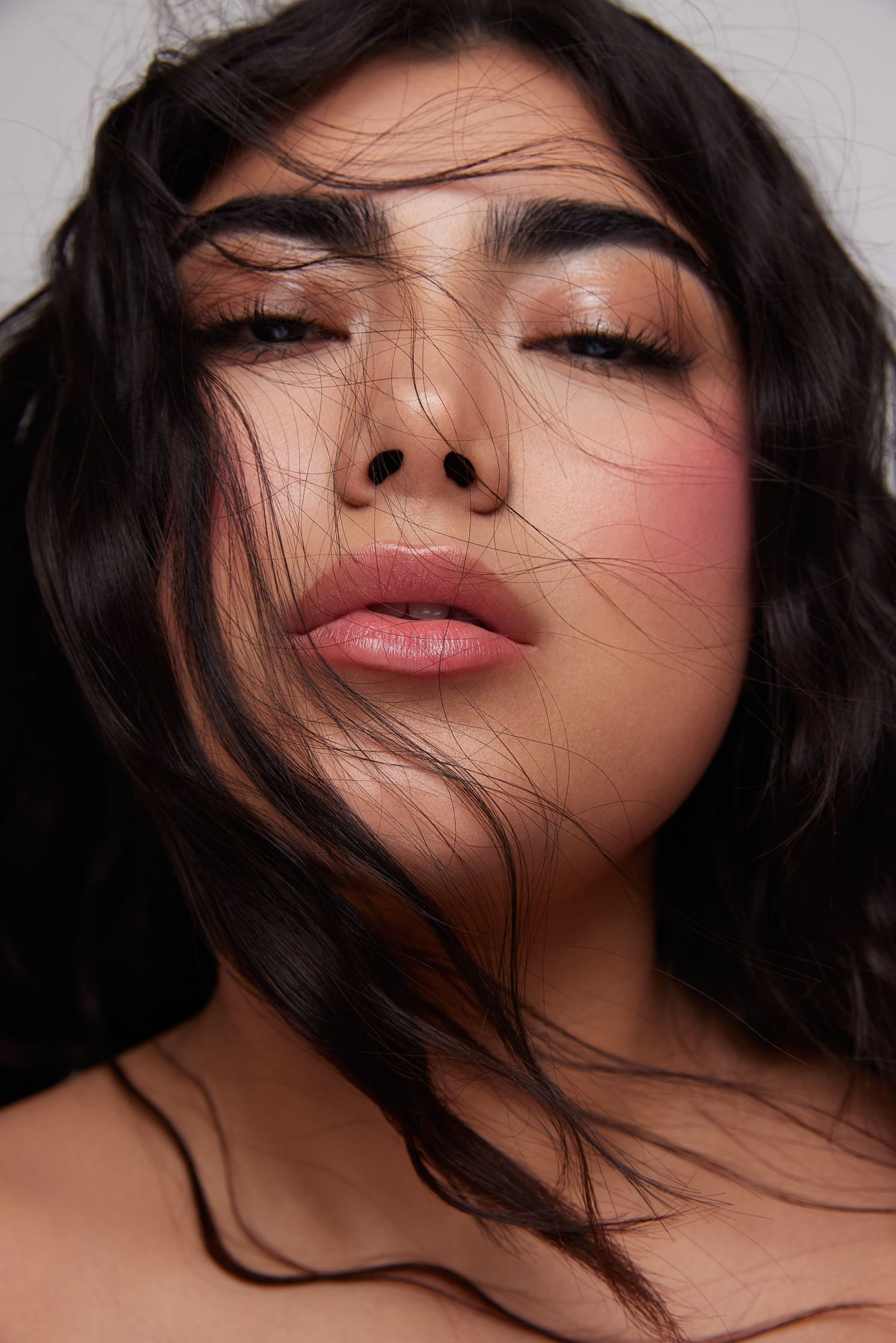 a woman with long dark hair and pink lipstick