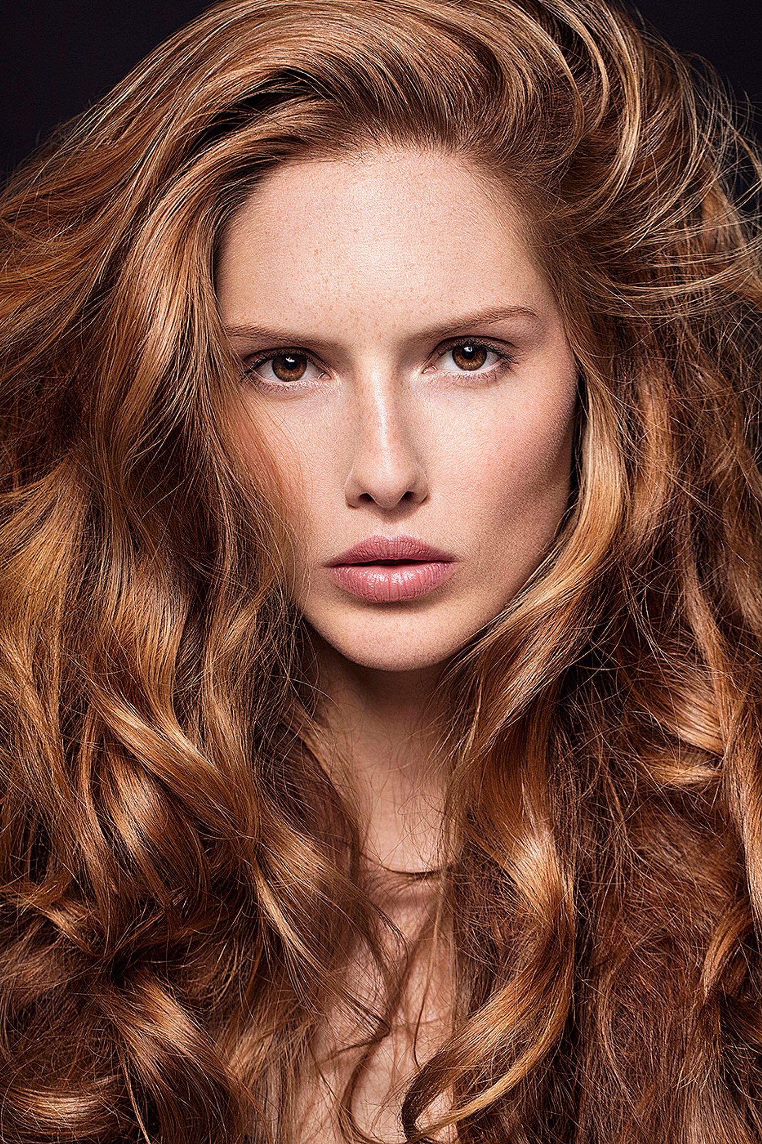 a woman with long curly hair posing for a photo retouche hamburg