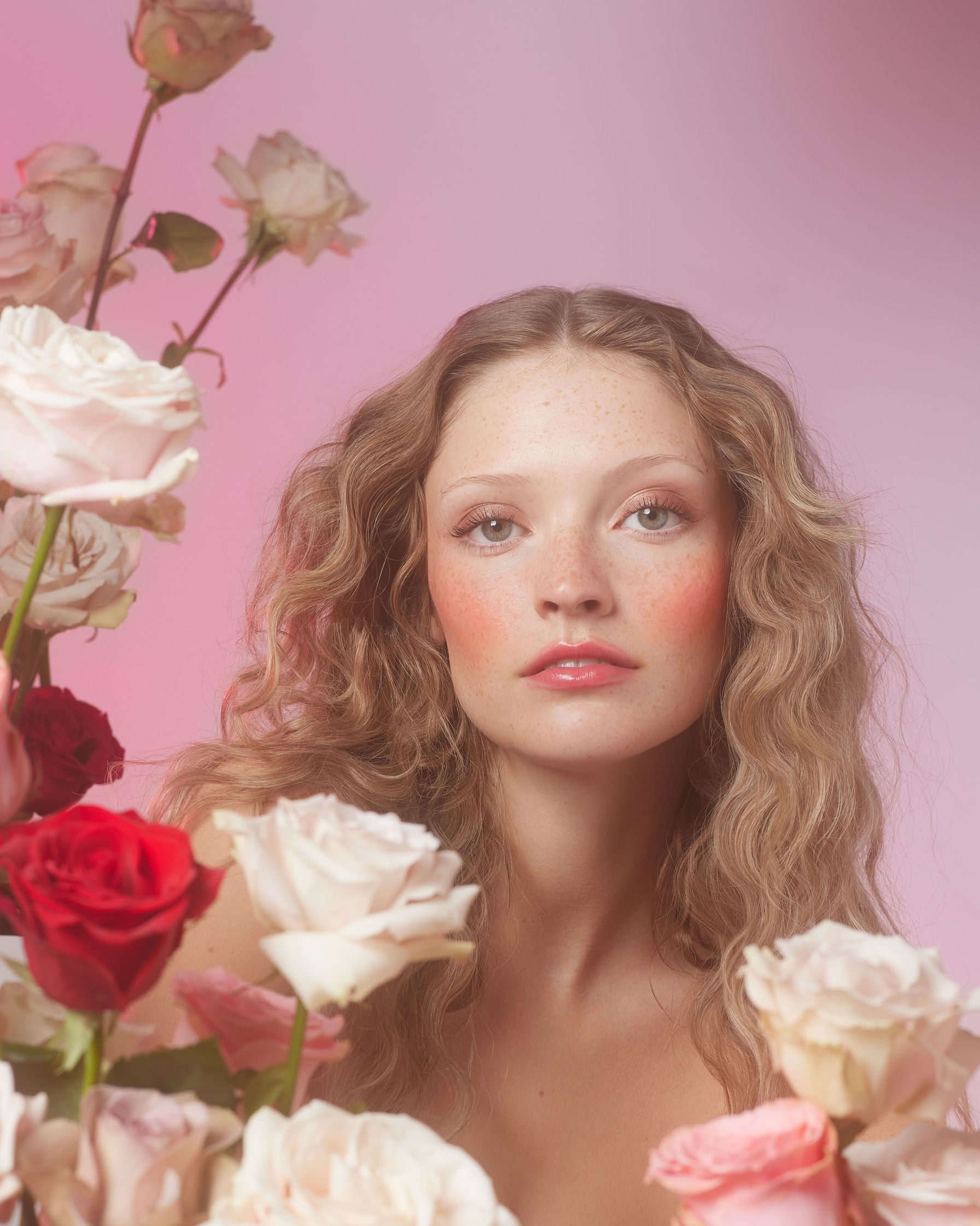 a young woman is posing in front of a bunch of roses