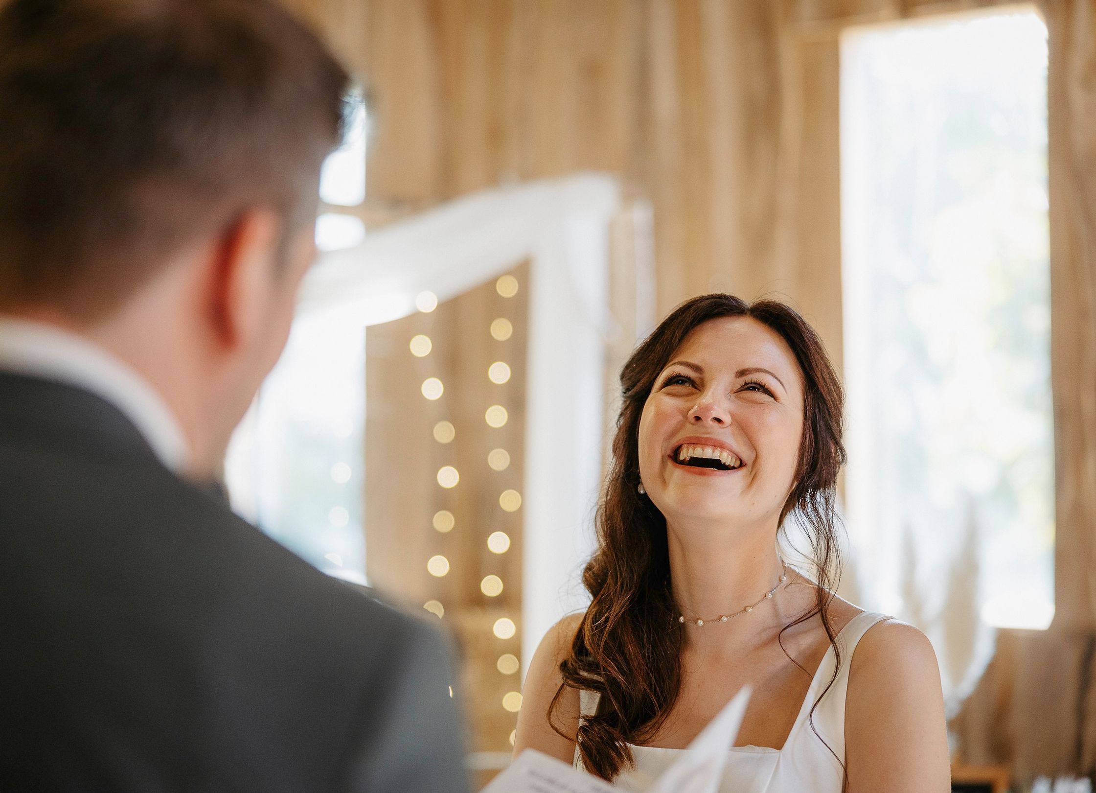 Eine Braut und ein Bräutigam lachen einander während ihrer Hochzeitszeremonie aus