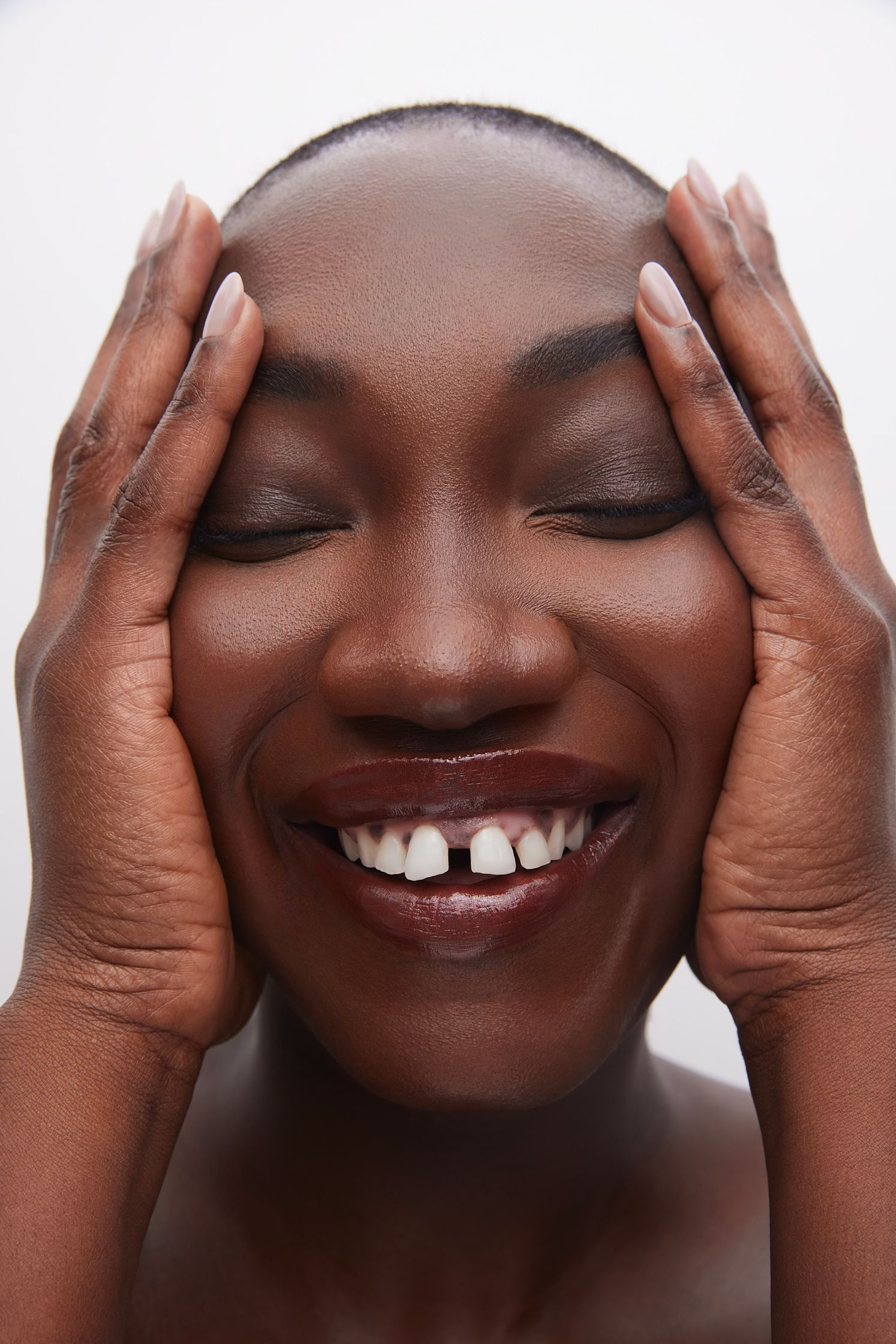 a black woman smiling with her hands on her face