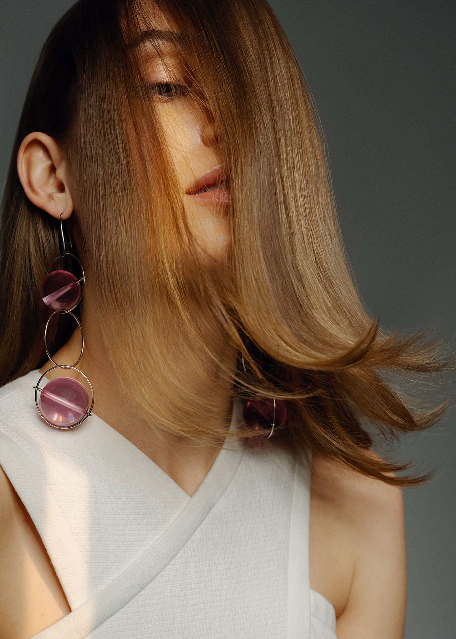 a woman with long hair and purple earrings