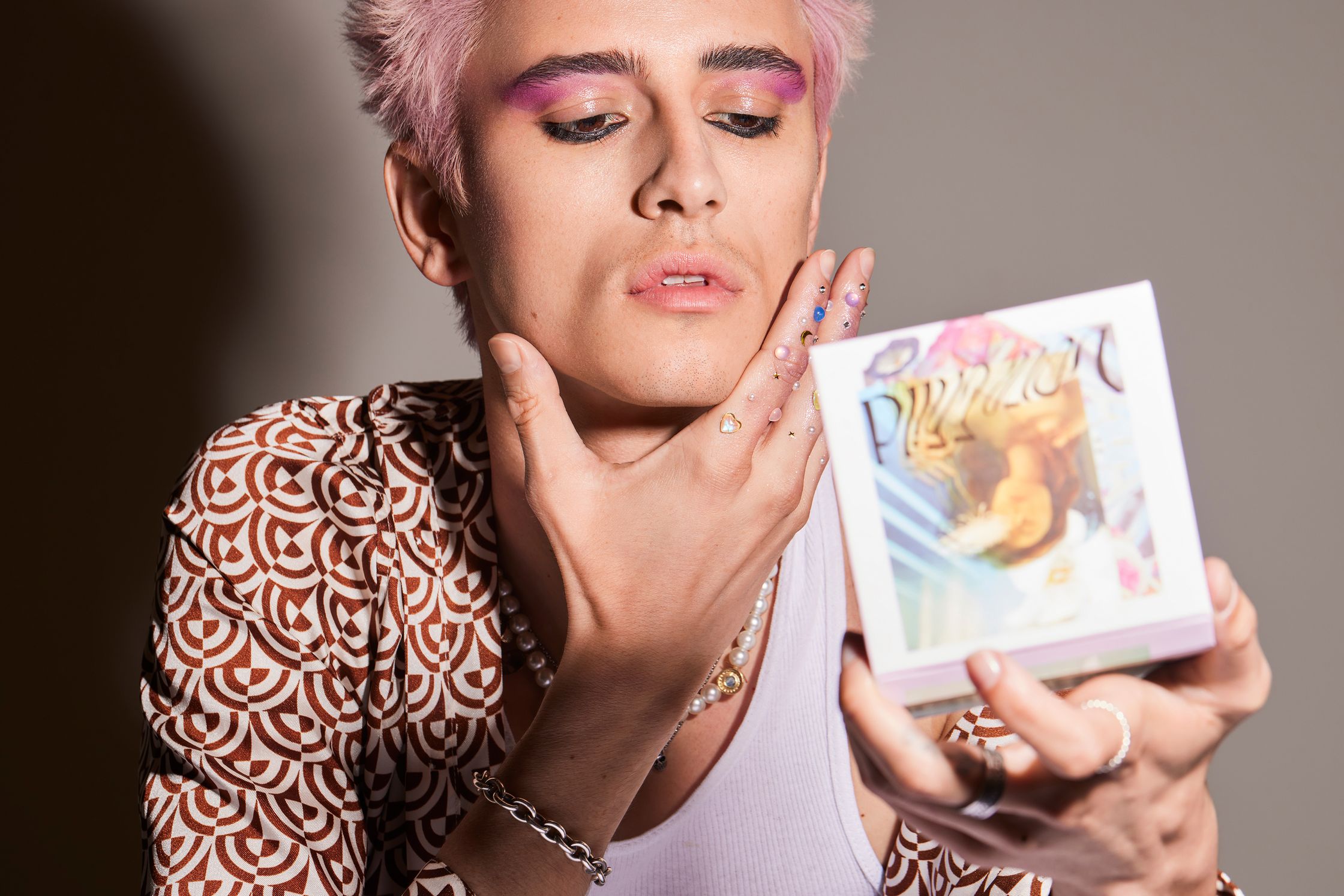 a man with pink hair holding a book