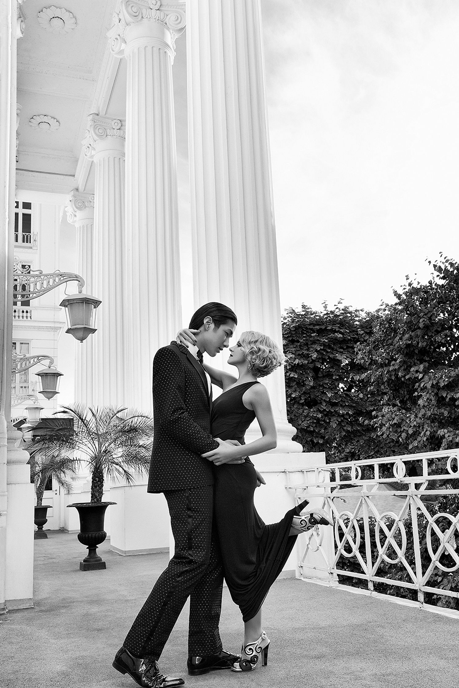 a black and white photo of a couple posing in front of columns advertising retouch hamburg