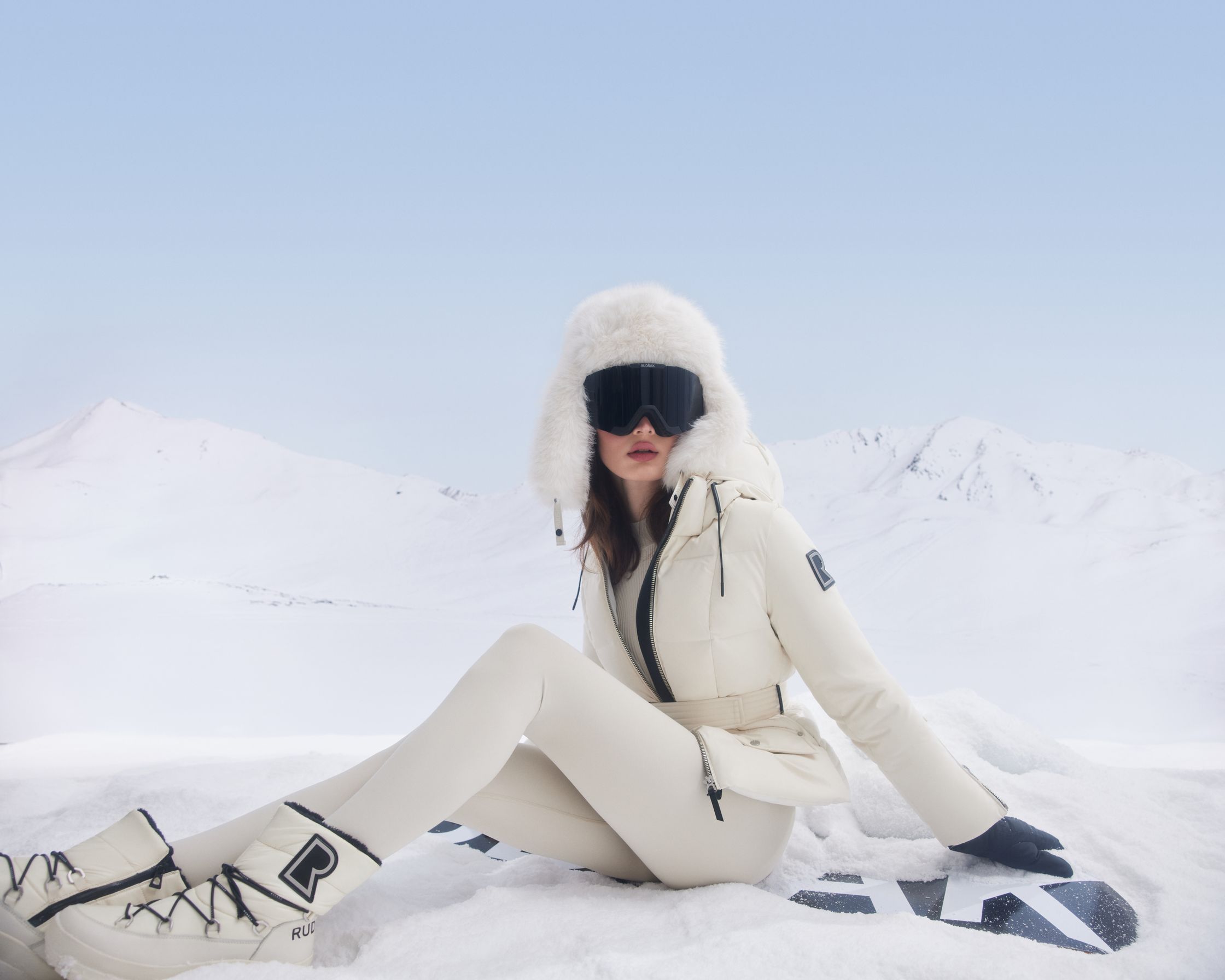 a woman sitting on a snowboard in the snow