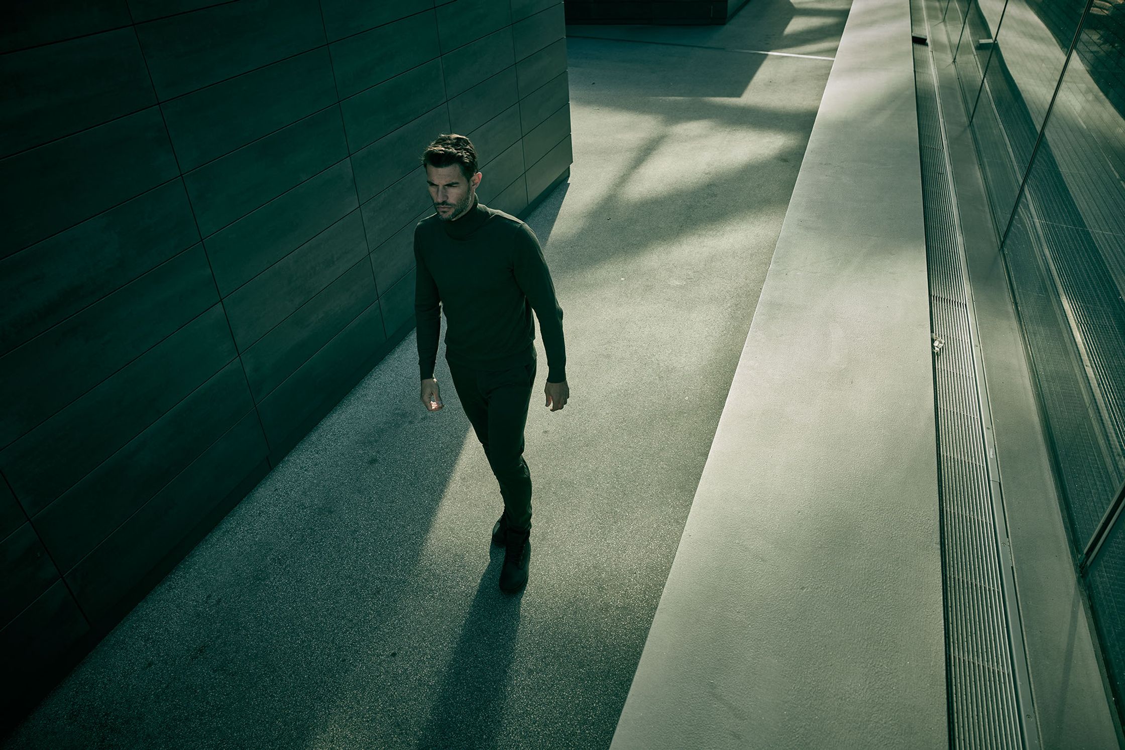 a man in a black suit walking down a hallway