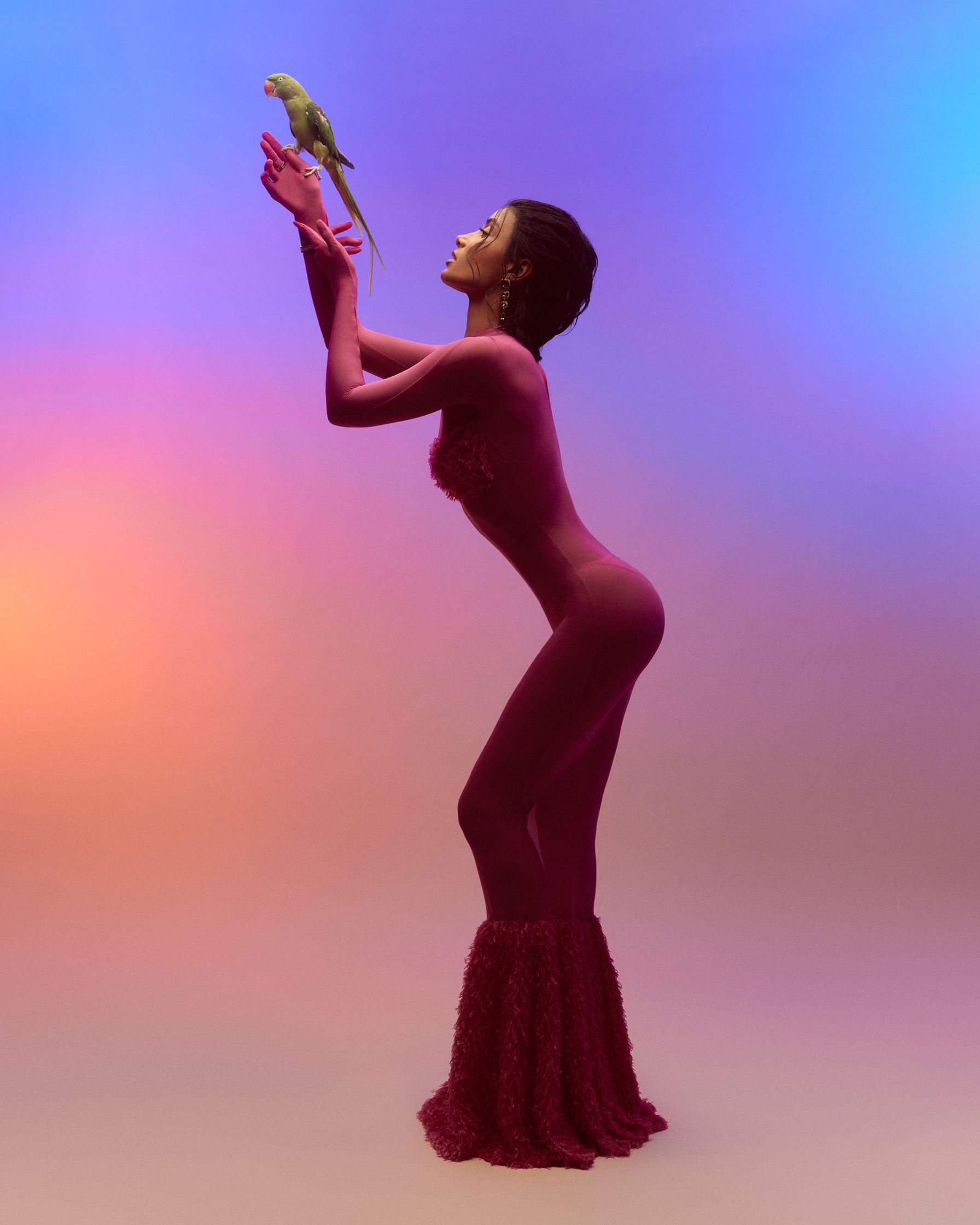 a woman in a pink bodysuit holding a parrot