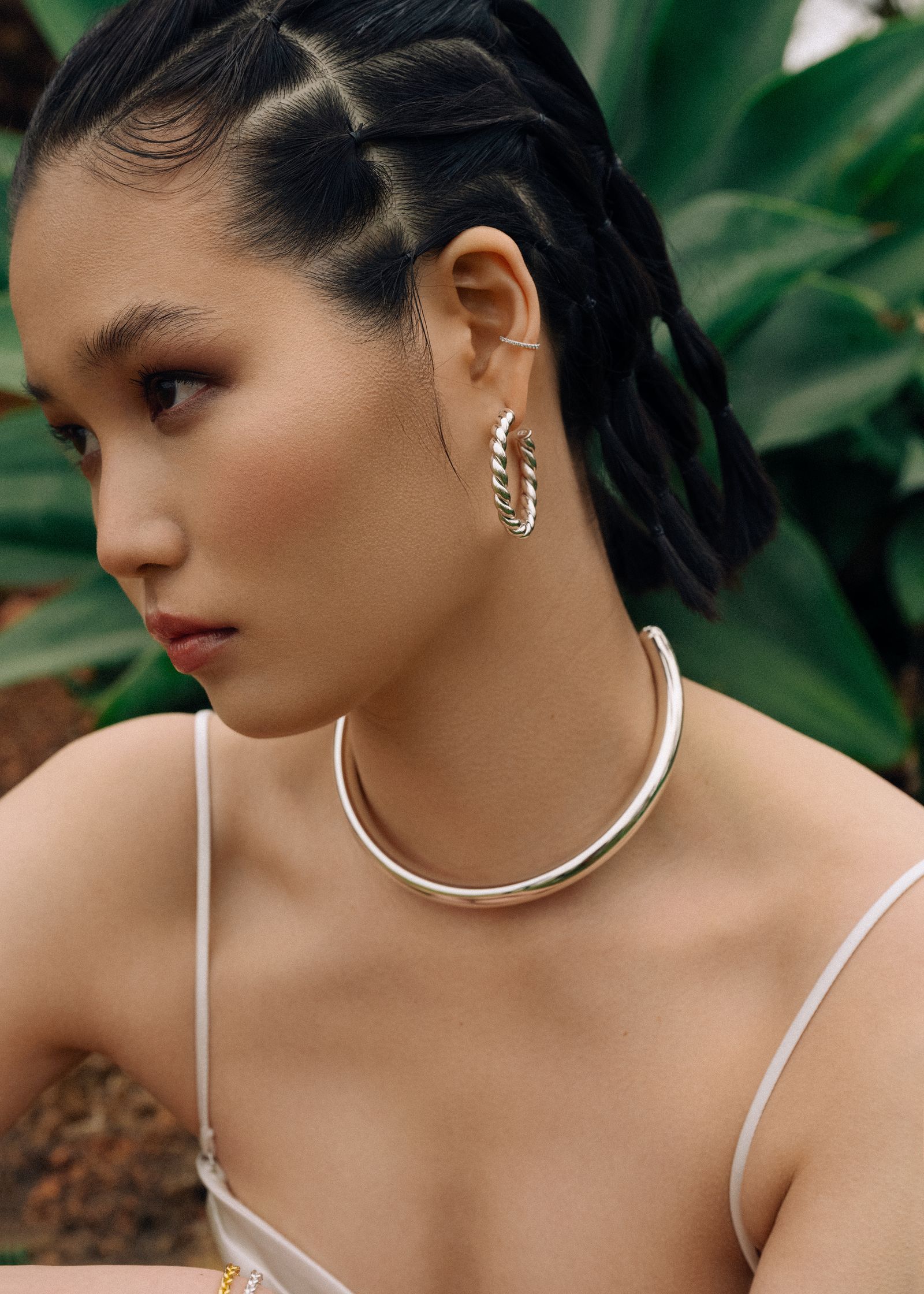 a woman wearing a white top and silver hoop earrings