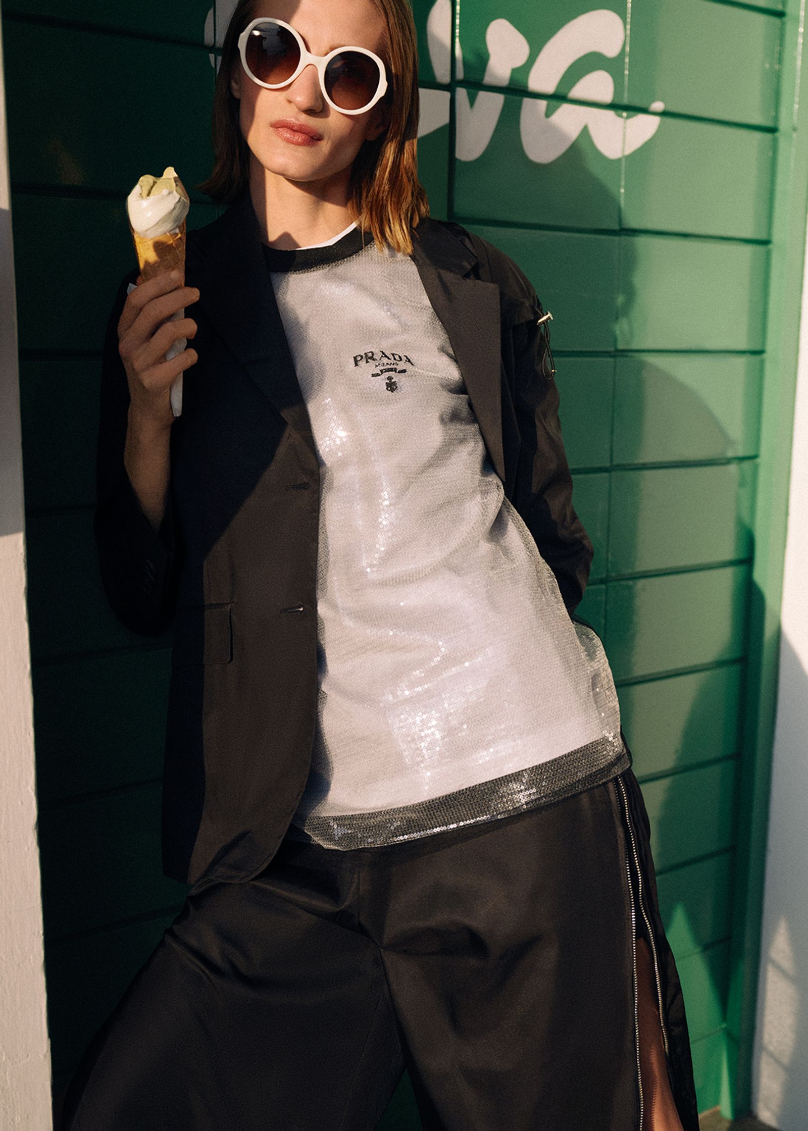 a woman is holding an ice cream cone in front of a green building