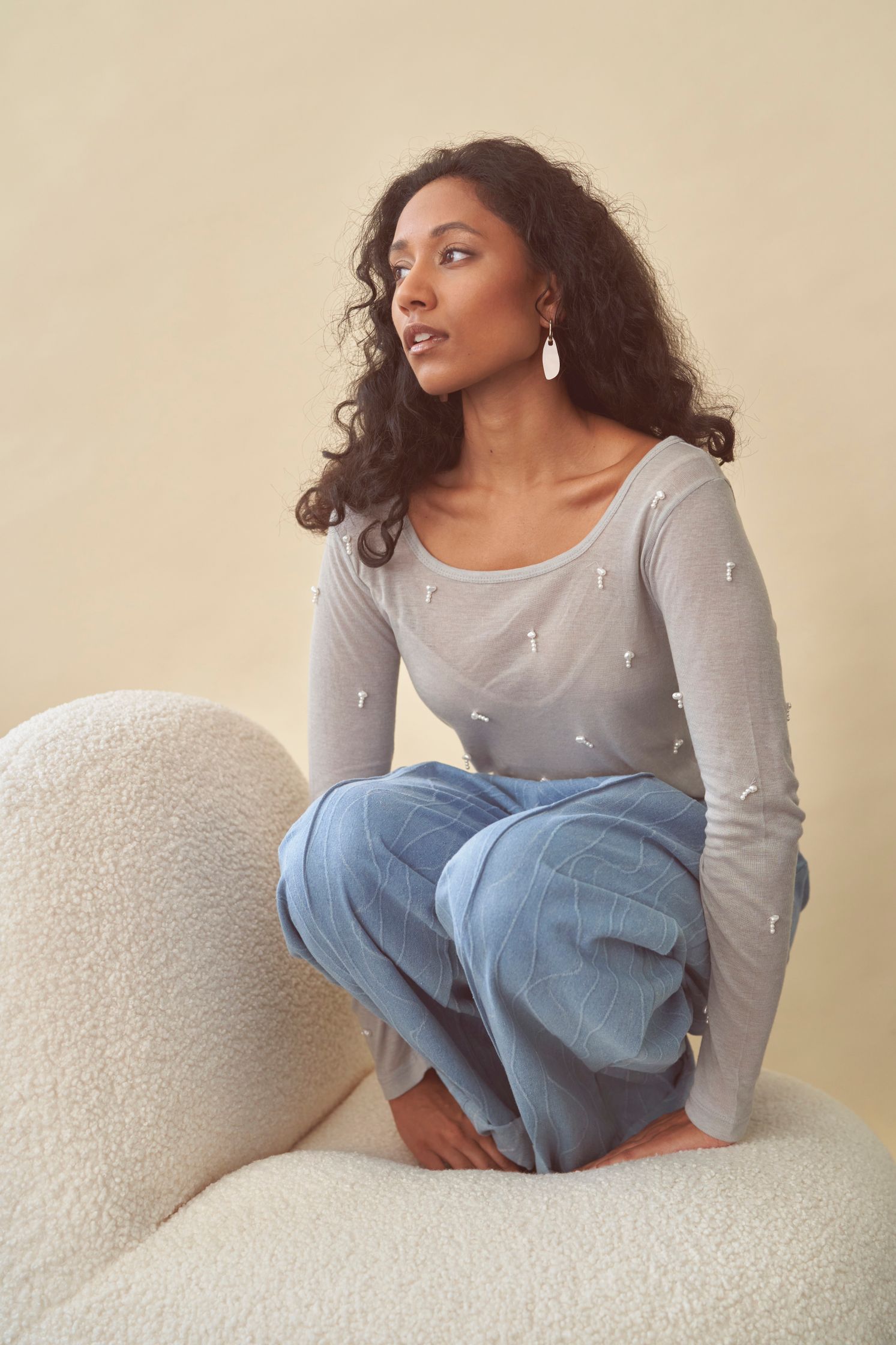 Model Devi Boddu wearing a light blue sweater, jeans, and Vanto earrings. Hair and makeup by Denise Dedich.