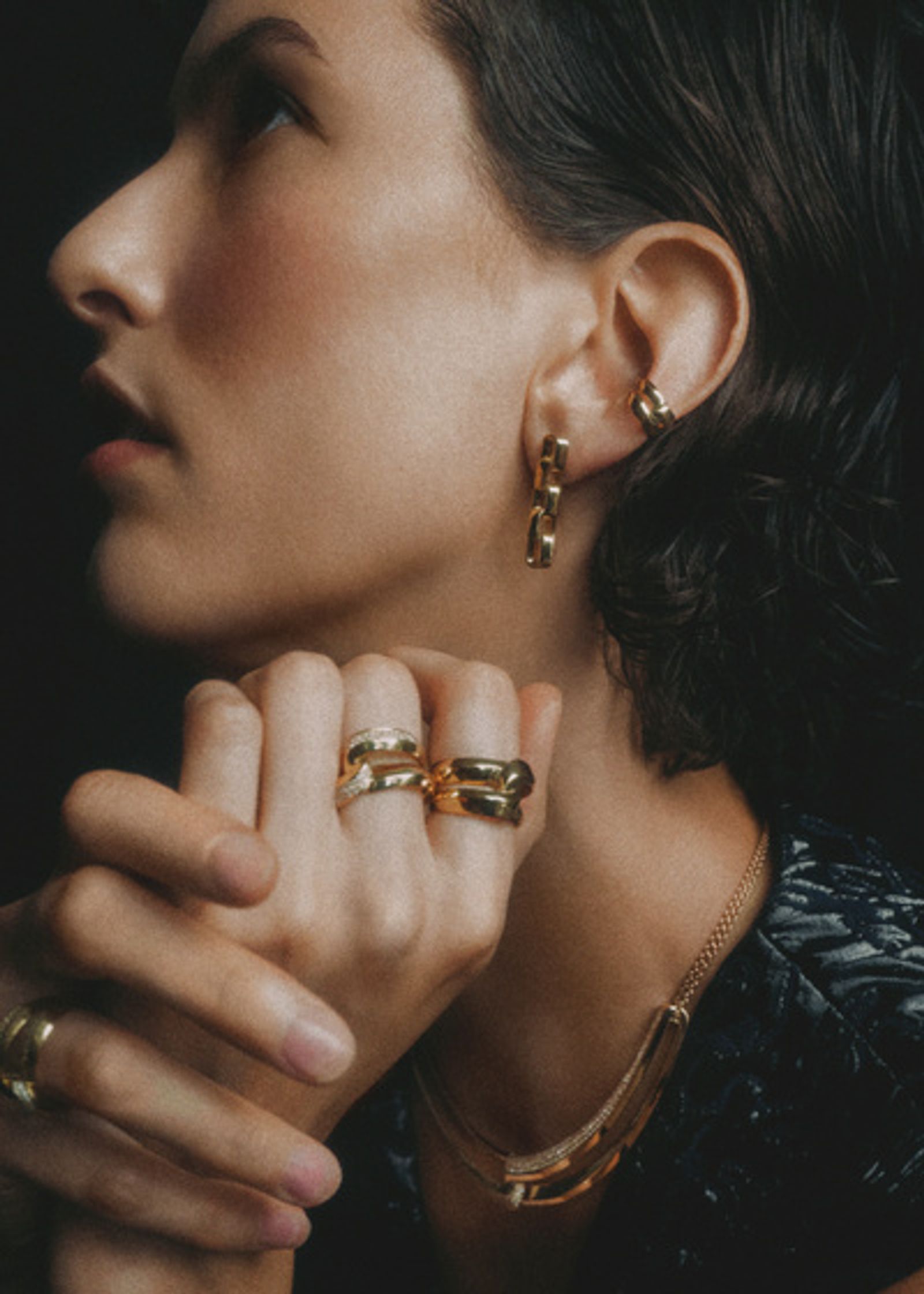 a woman wearing a gold ring and earring