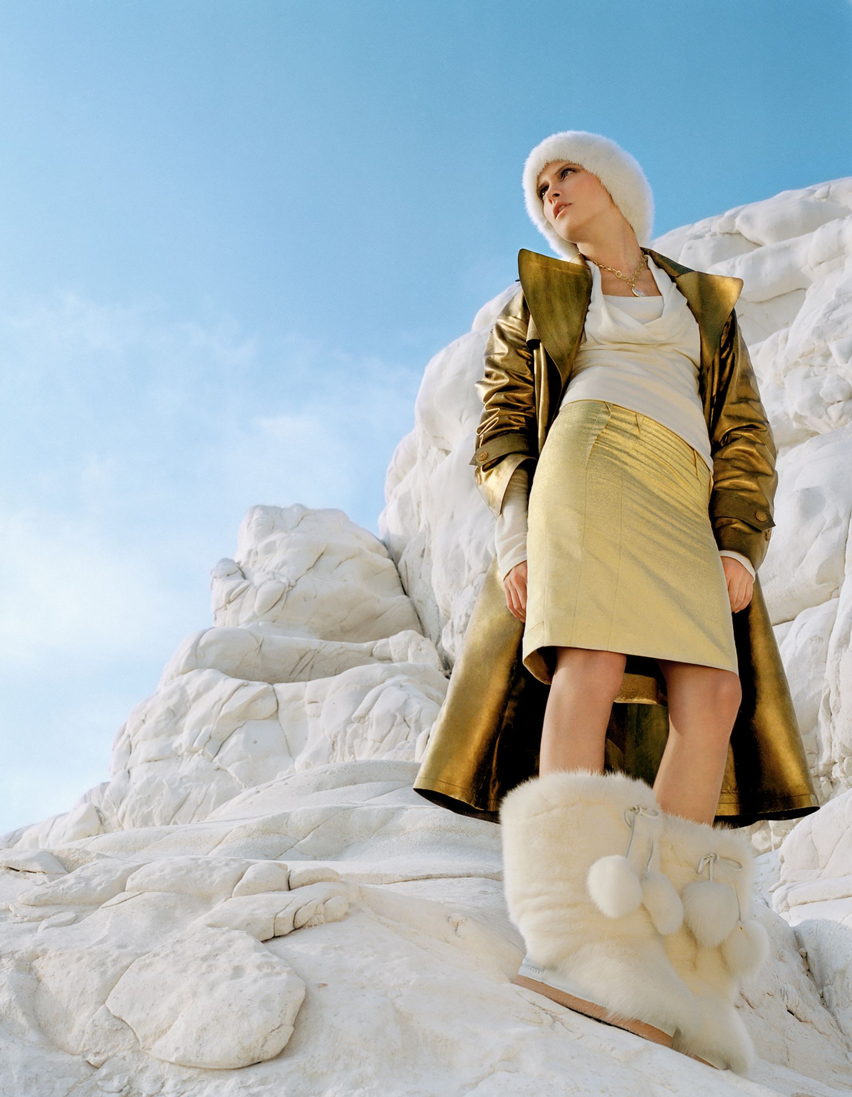 a woman in a gold coat standing on top of a snowy mountain editorial retouching hamburg