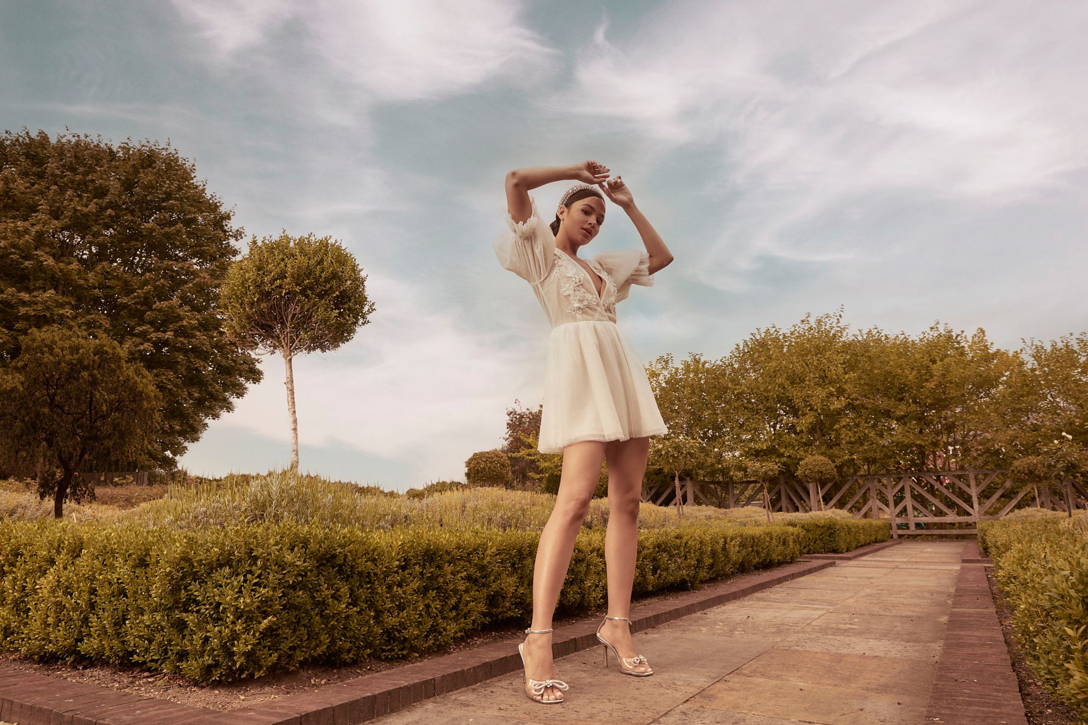 a woman in a white dress posing in a garden