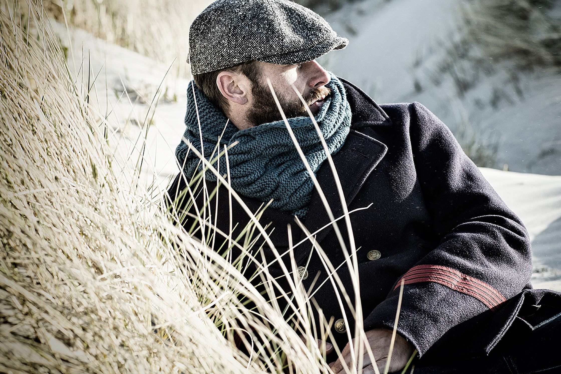 a man wearing a hat and scarf in the sand retouch hamburg