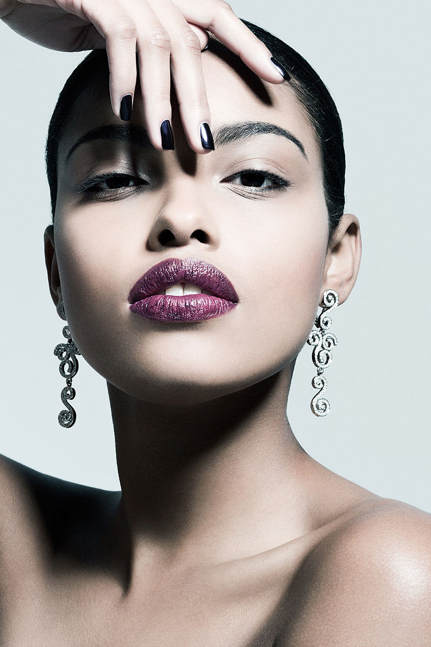 a black woman with purple nails and earrings posing for a photo beauty post production