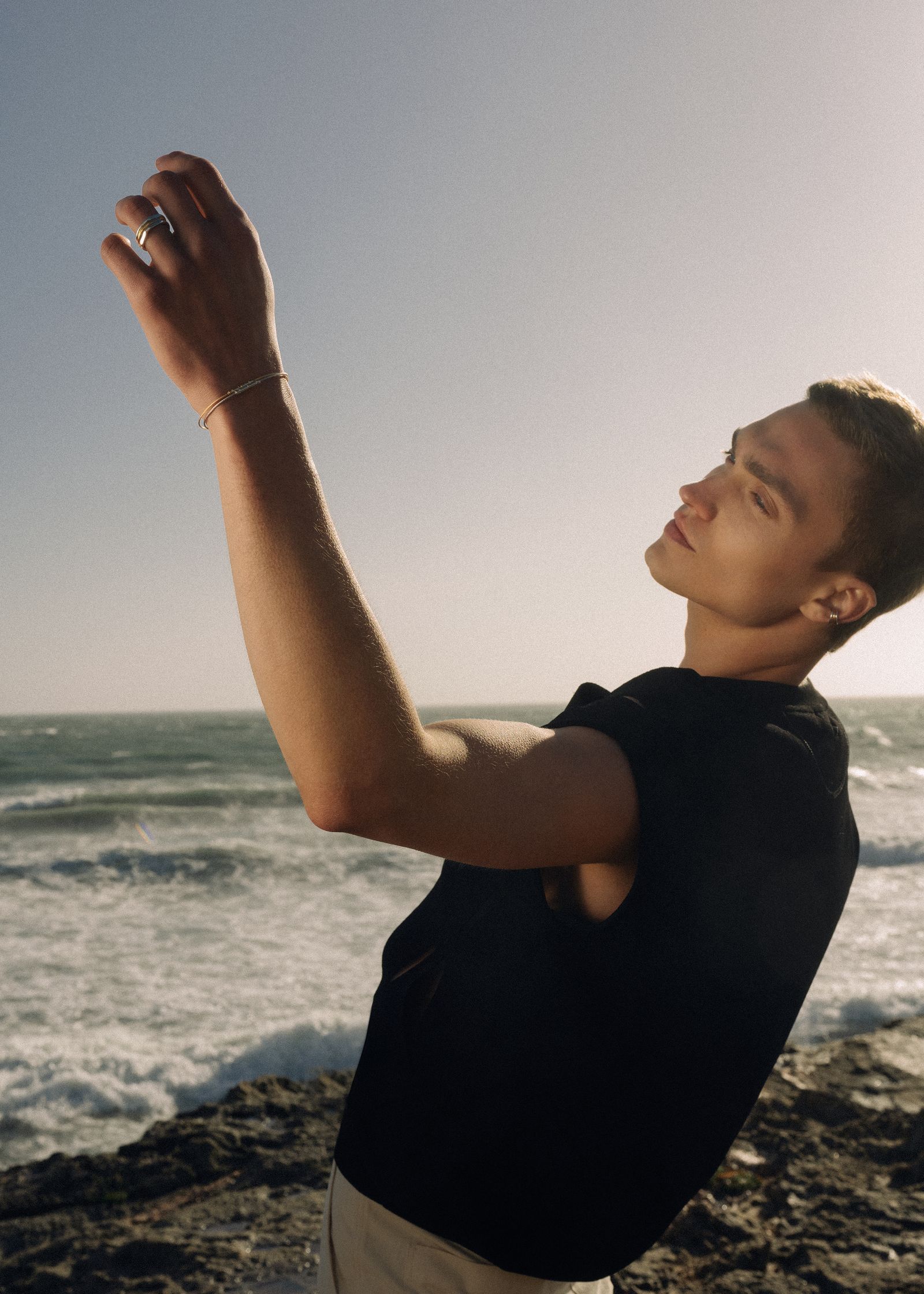 a man standing on a rocky beach holding a cell phone