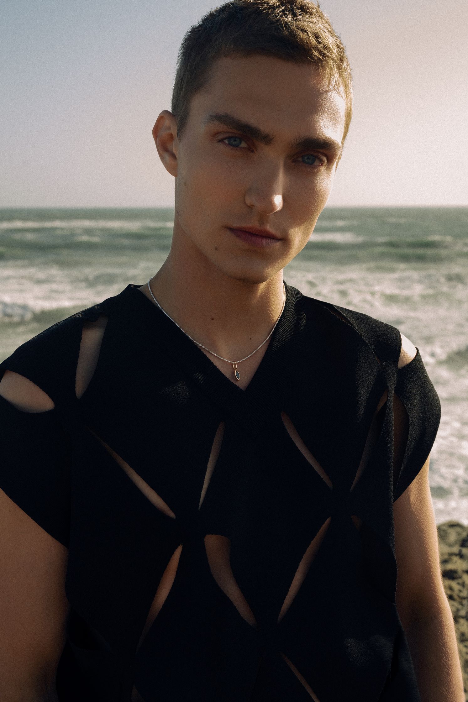 a young man in a black shirt standing by the ocean