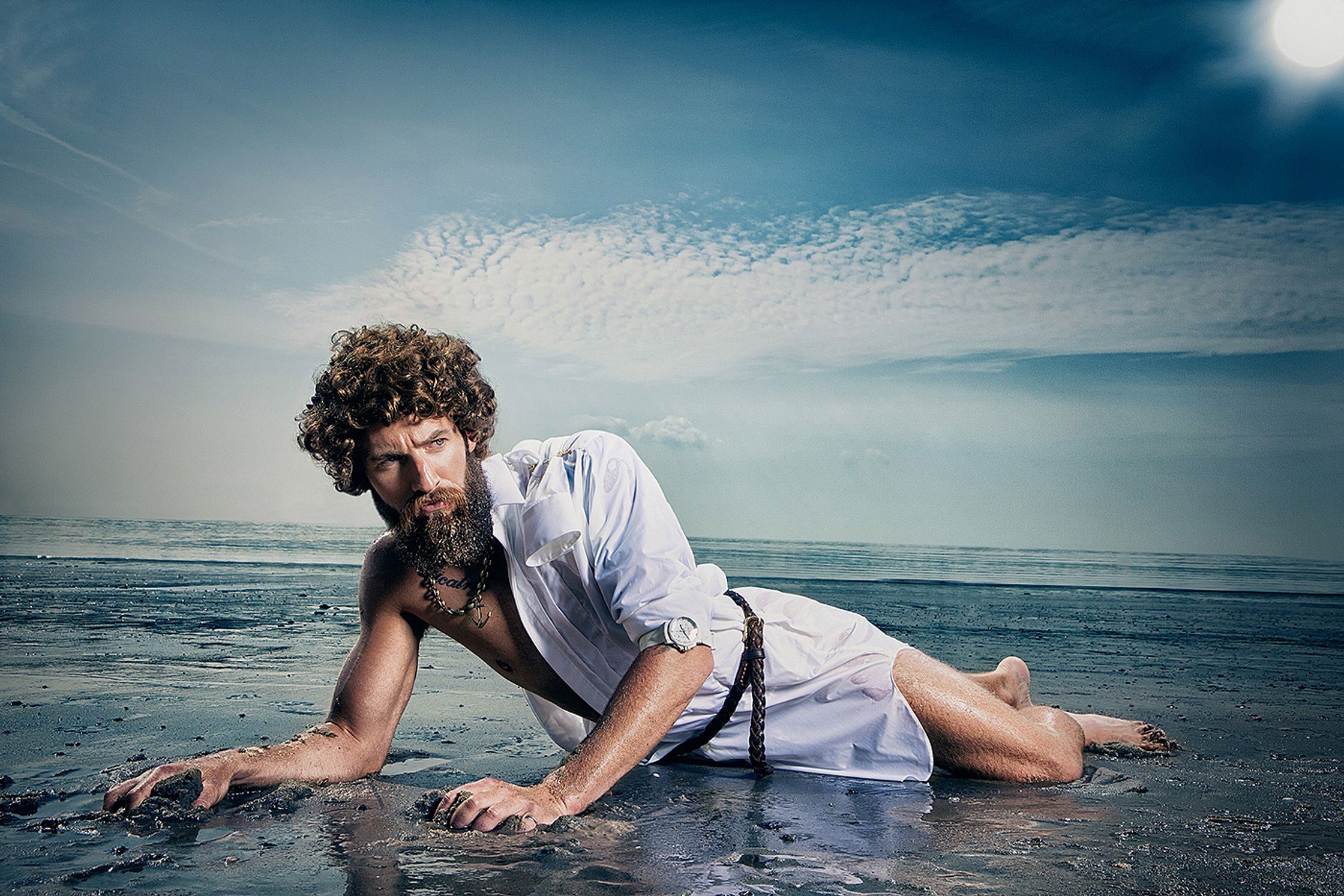 a man laying in the sand on a beach Creative Retouching Hamburg