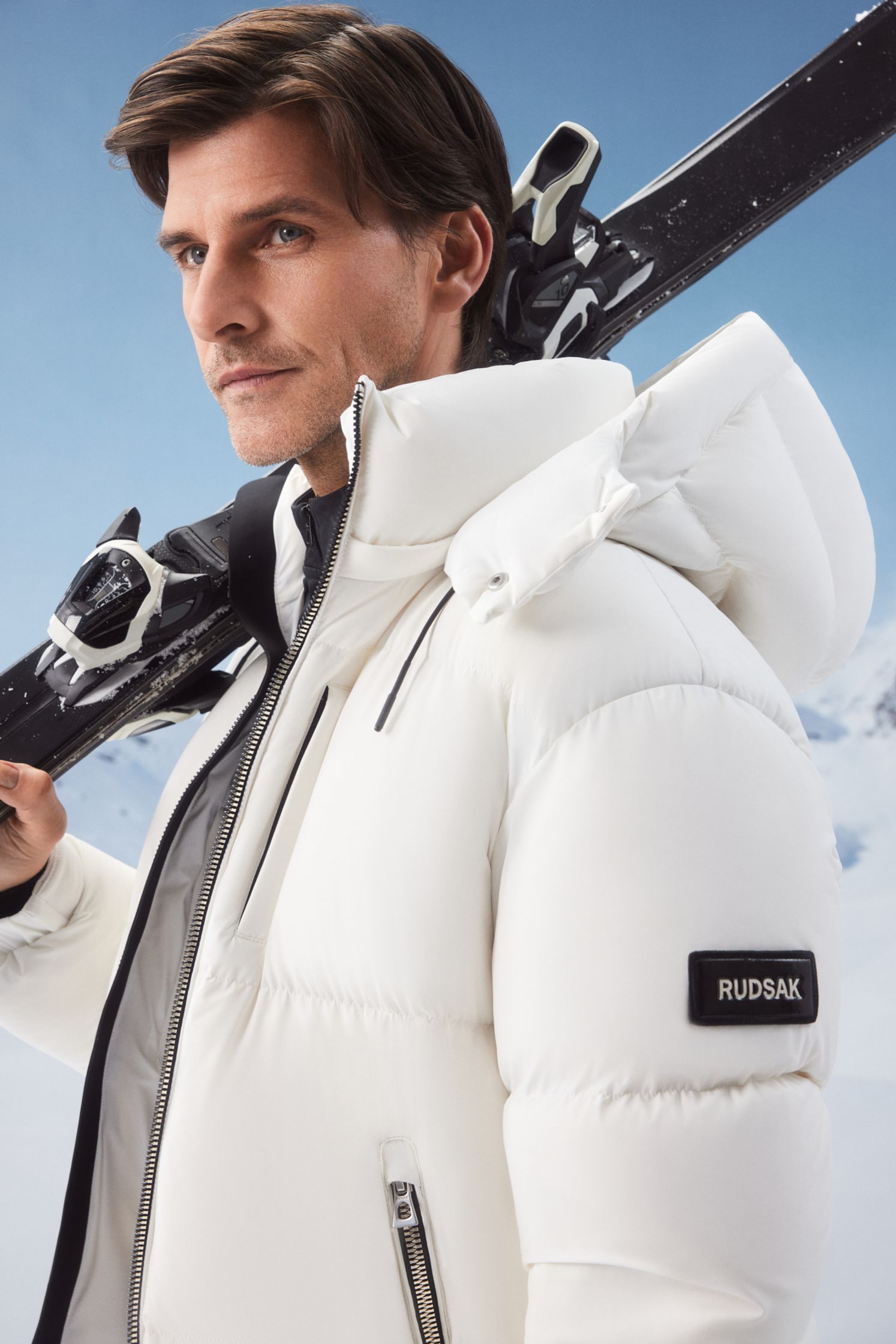 a man in a white puffer jacket holding skis