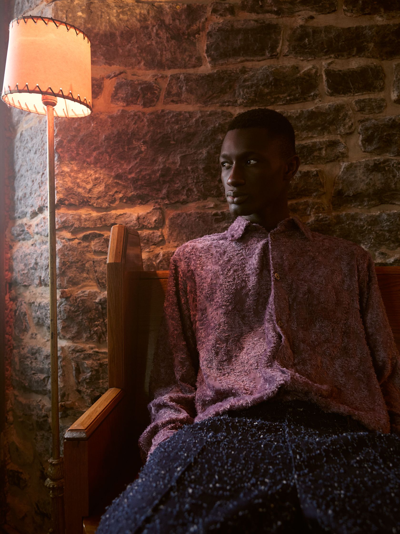 a black man sitting in a chair with a lamp