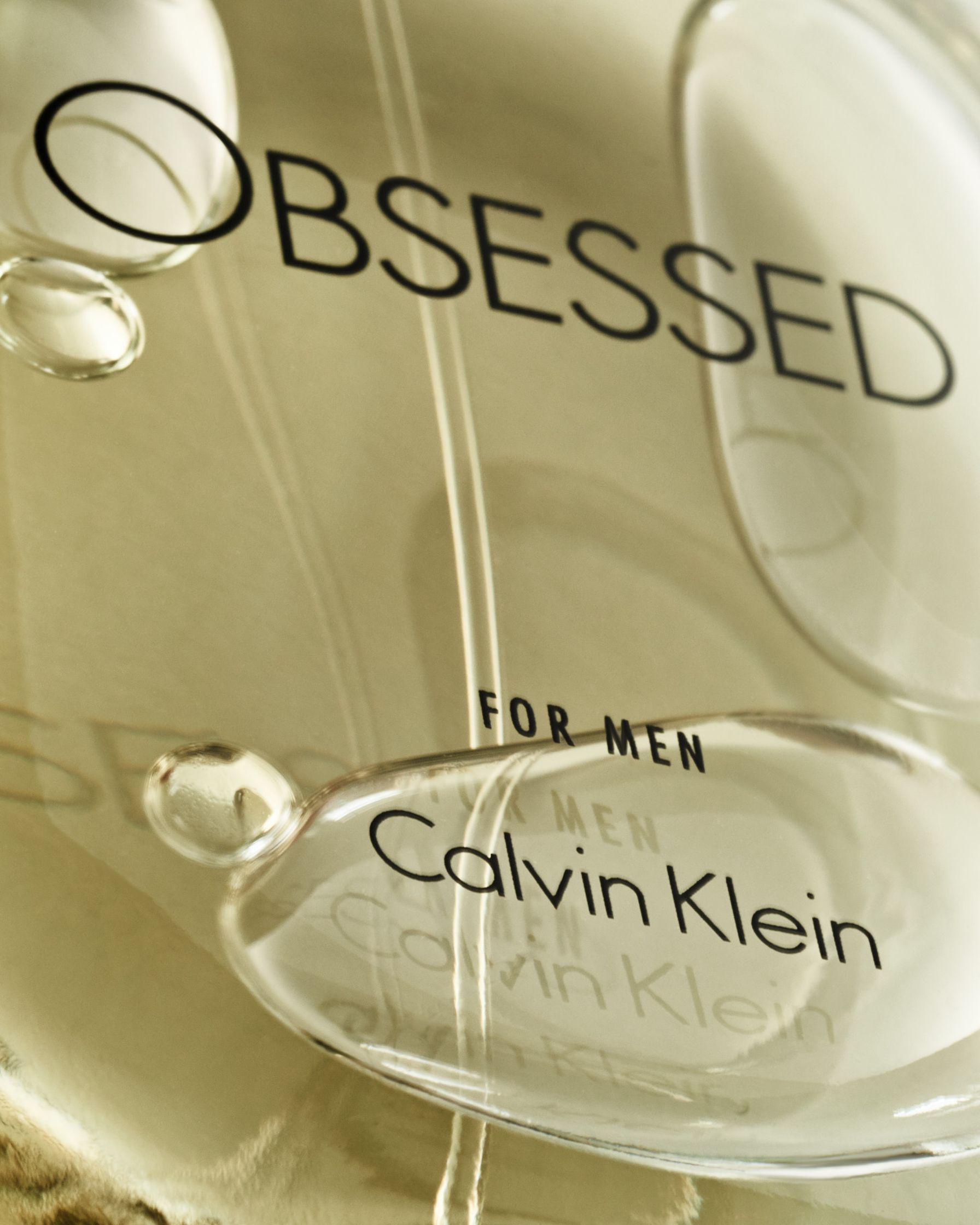 Extreme close-up of the Calvin Klein Obsessed for Men bottle label, with emphasis on the minimal and sleek typography.