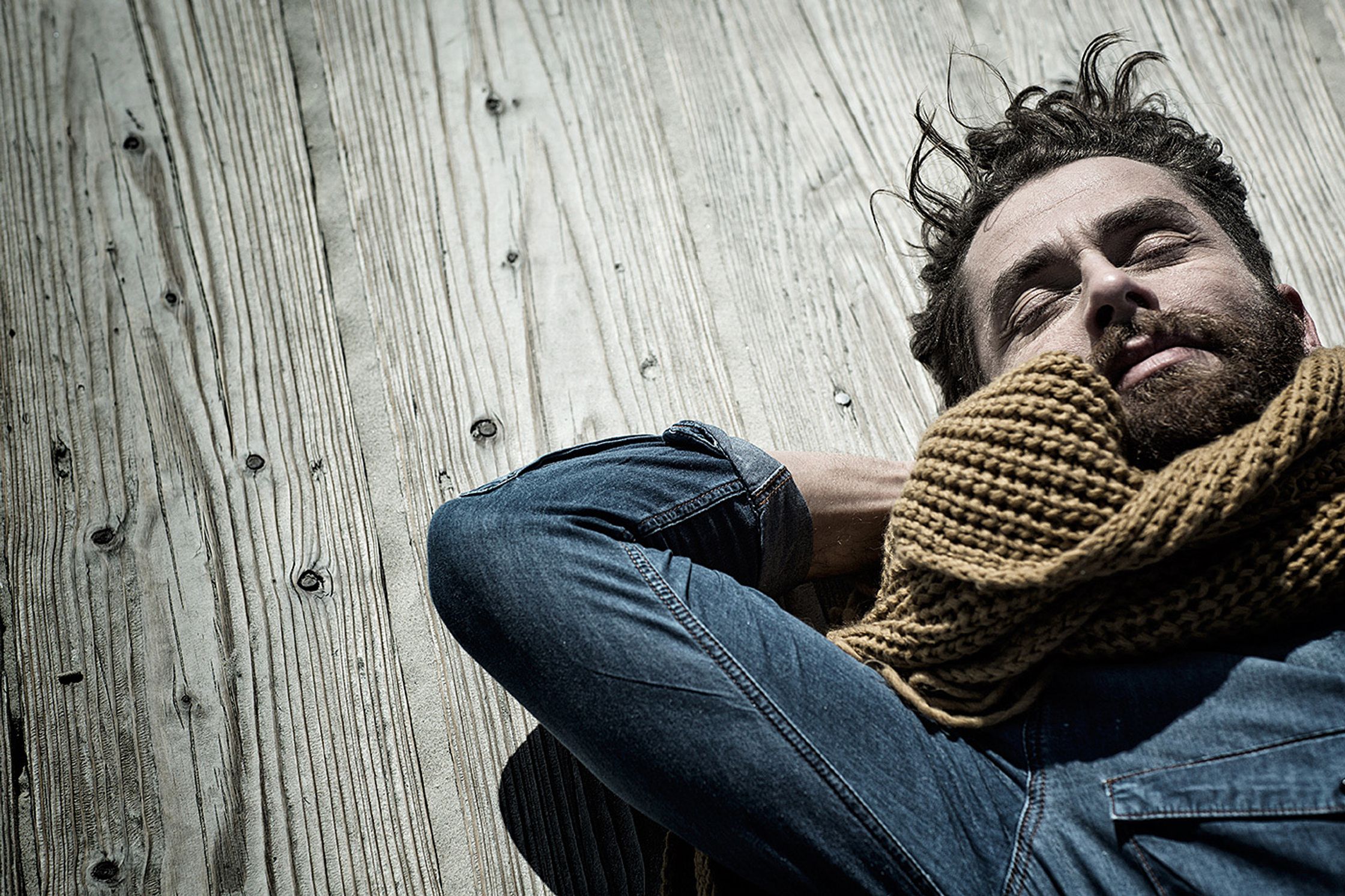 a man with a scarf on his head laying on a wooden wall retouche image campaign