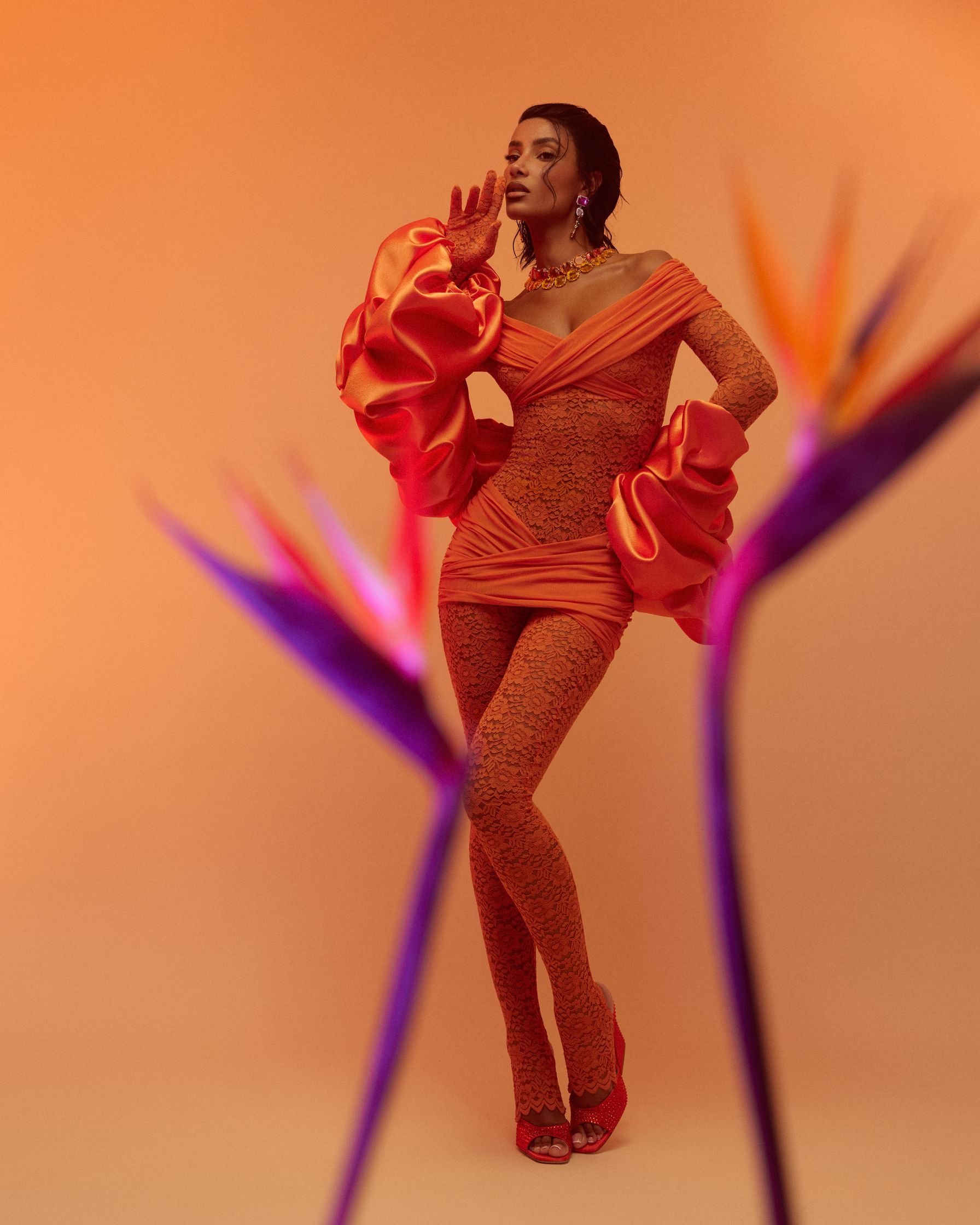 a woman in an orange dress posing in front of flowers