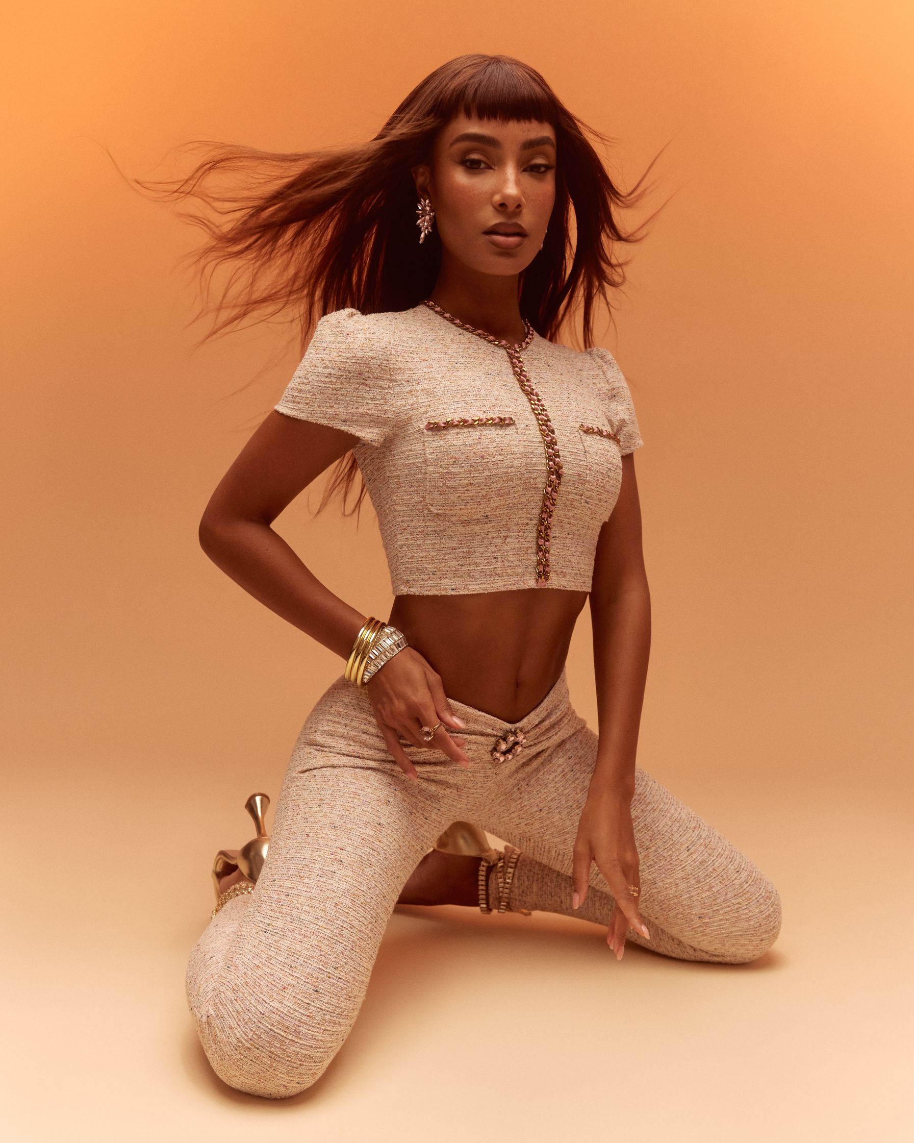 a woman in a beige outfit posing on the ground
