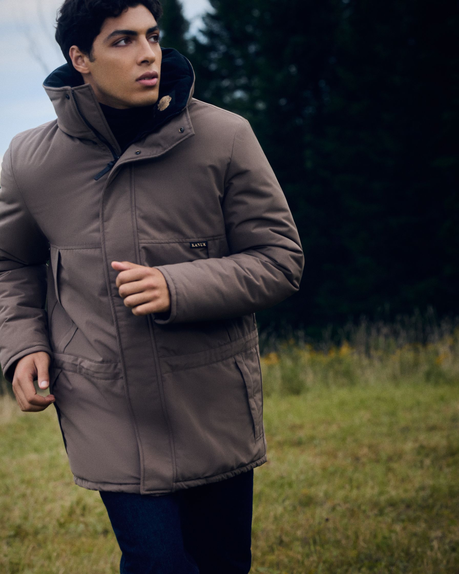 a man in a brown parka running in a field