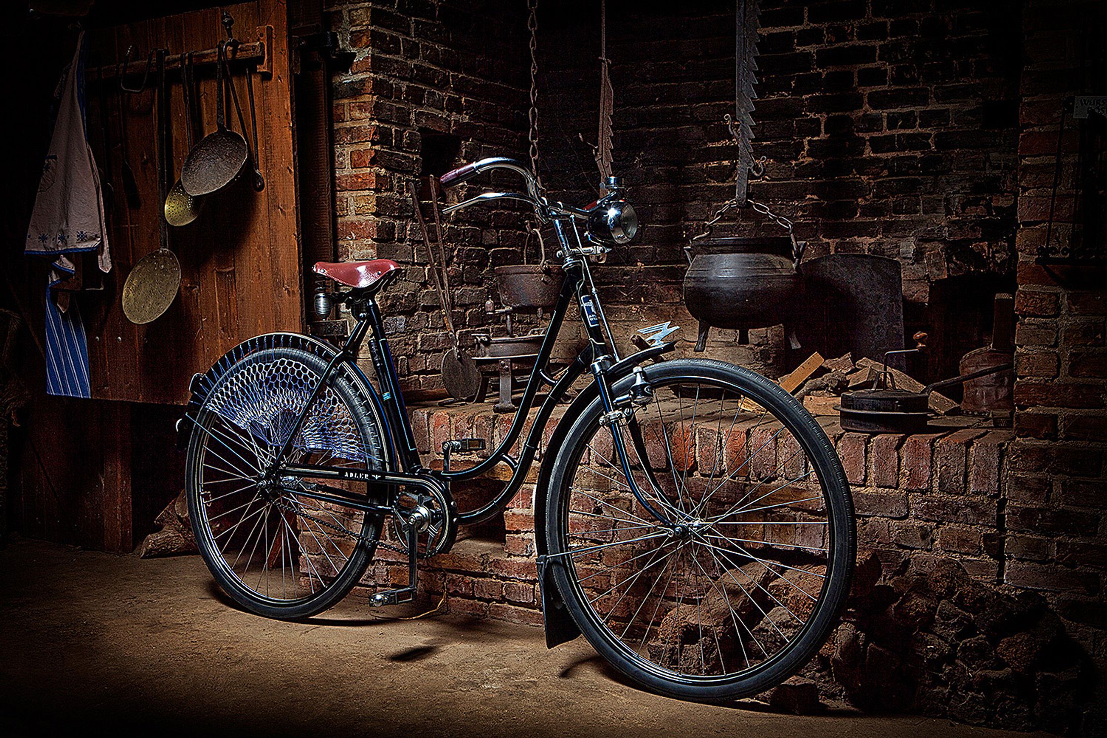 a old black bicycle leaning against a brick wall Bildbearbeitung Hamburg